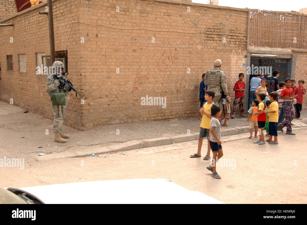 U.S. Army Pfc. Jon Pierre Johnson, of 1st Armored Division, 2nd Stryker Cavalry Regiment, 4th Squadron Quick strike Troop, keeps an eye on the local children during a meeting at a police station in the Muhaila neighborhood of Baghdad, Iraq, on Oct. 1. The visit was part of an ongoing validation of Iraqi police in the neighborhood. Validation of Iraqi police 62349 Stock Photo