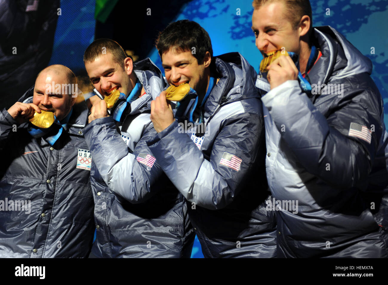 OLY1014-TeamHolcombBitesGold5663.jpg: Former U.S. Army World Class Athlete Program bobsledder Steven Holcomb and teammates Justin Olsen, Steve Mesler and Curt Tomasevicz bite their gold medals Saturday night at Whistler Medals Plaza after winning the Olympic four-man bobsled crown earlier in the day at Whistler Sliding Centre. Photo by Tim Hipps, FMWRC Public Affairs USA-1 4 man bobsleigh team with gold medals at 2010 Winter Olympics 2010-02-27 Stock Photo