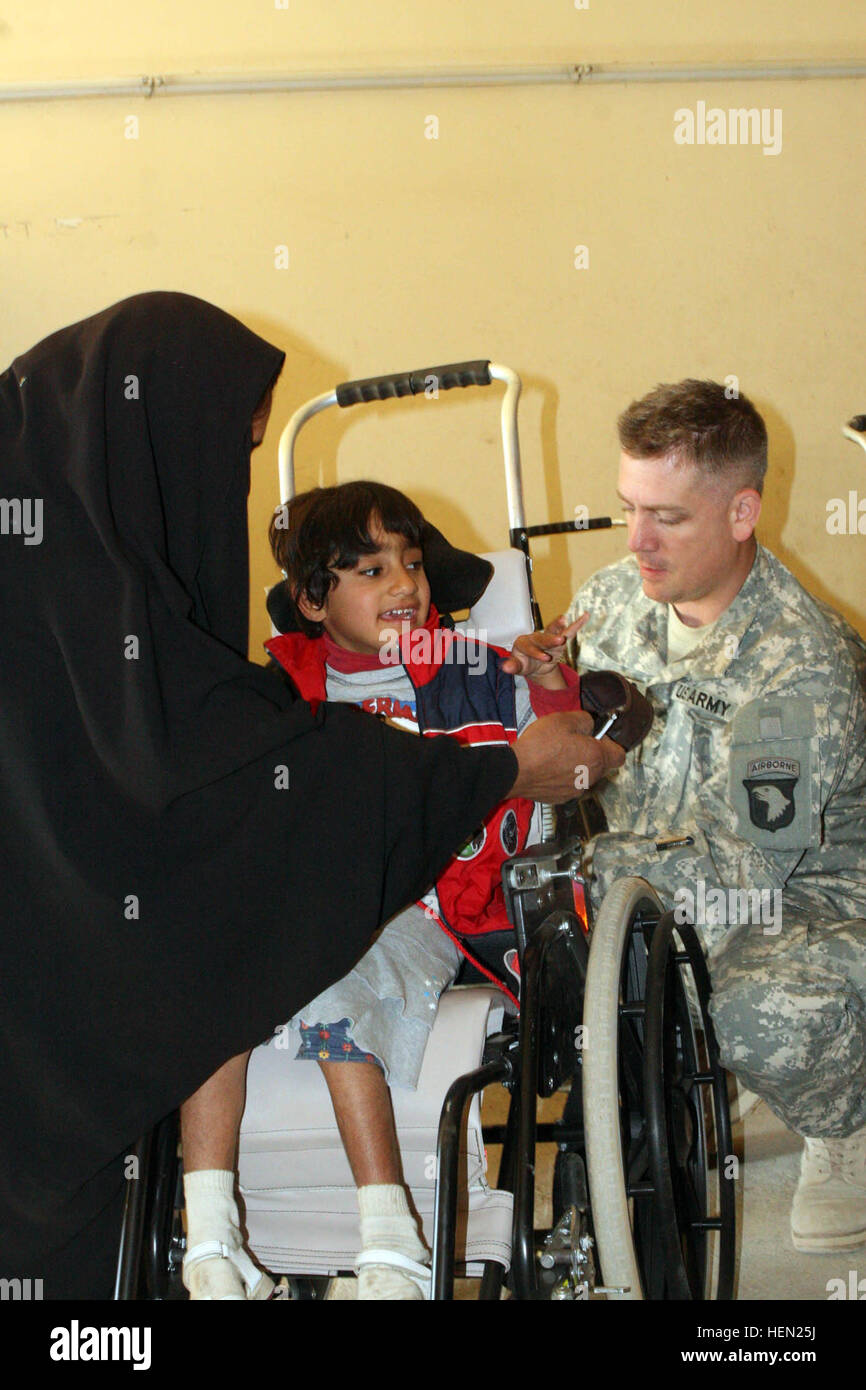 Sergeant Lonnie Todero, a medic with 1st Squadron, 33rd Cavalry, 3rd Brigade Combat Team, 101st Airborne Division (Air Assault), makes adjustments to Zeanib Saad Al Amary's wheelchair Dec. 13 at Radwaniyah Palace Complex Civil-Military Operations Center. Iraqi Children Get New Wheels 68850 Stock Photo