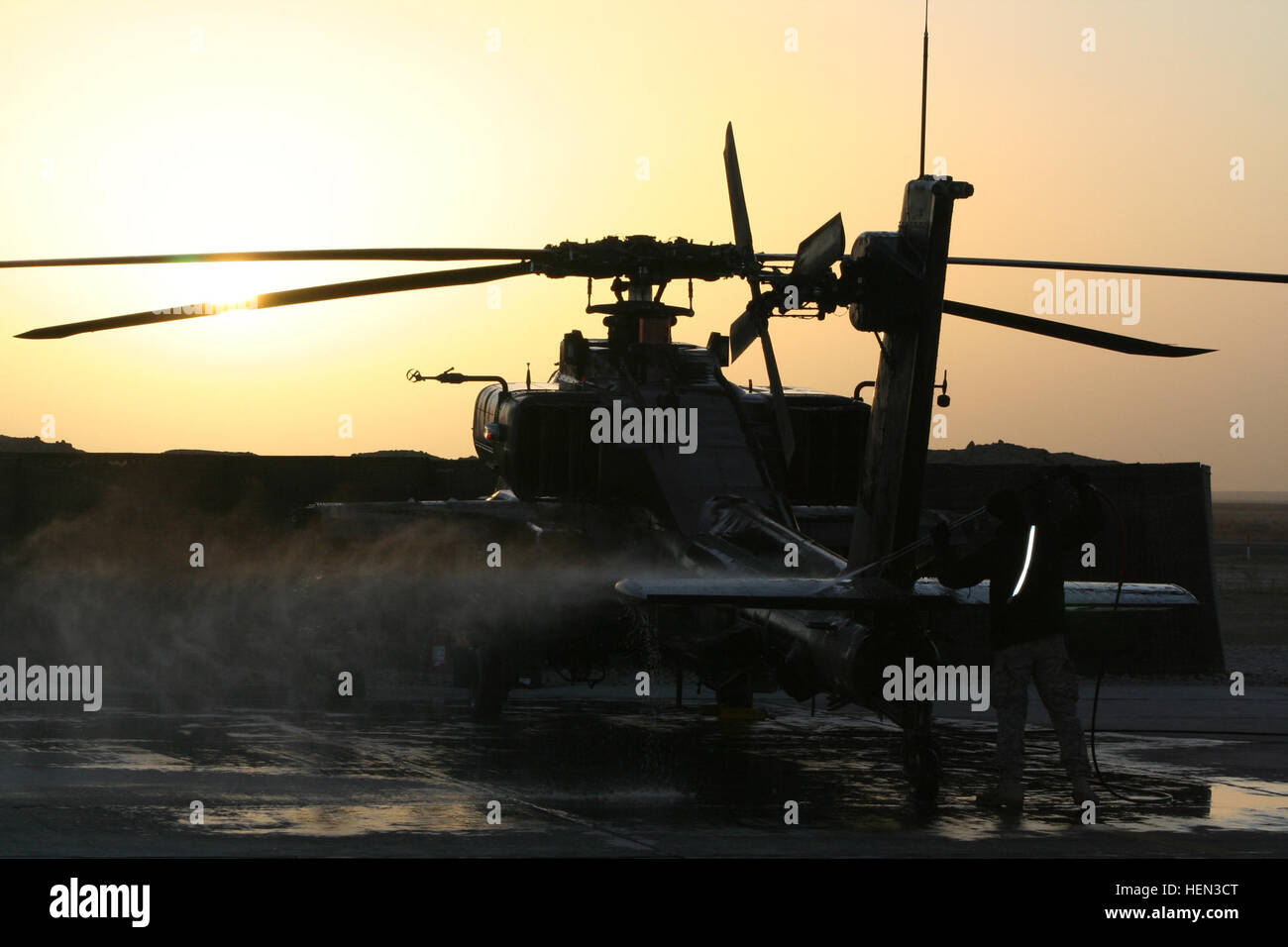 An AH-64D Apache Longbow belonging to 1st Attack Reconnaissance Battalion, 1st Aviation Regiment, is washed down by ground crew in preparation for a night mission on Dec. 22. The 1-1 ARB “Gunfighter” air and ground crews work around the clock sustaining air operations and are part of the Combat Aviation Brigade, 1st Infantry Division, from Fort Riley Kan., flying in support of Task Force Iron, 1st Armored Division, in northern Iraq. (Photo by U.S. Army Maj. Enrique T. Vasquez) Mission at Sunset 70900 Stock Photo
