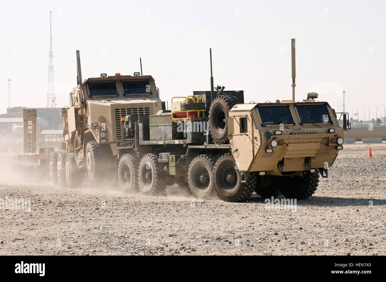 A Heavy Expanded Mobility Tactical Truck Wrecker tows a Heavy Equipment