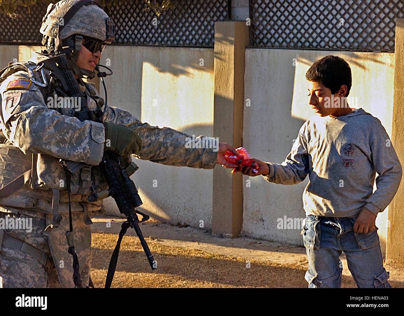 Sgt. Domingo Sagolili, a cavalry scout in 1st Platoon, Troop I, 3rd Squadron, 3d Armored Cavalry Regiment from Fort Hood, Texas, hands an Iraqi boy a bag of candy canes during a patrol in Mosul, Iraq, Feb. 4. Iron Hawk Soldiers maintain good relations with people of Mosul 76378 Stock Photo