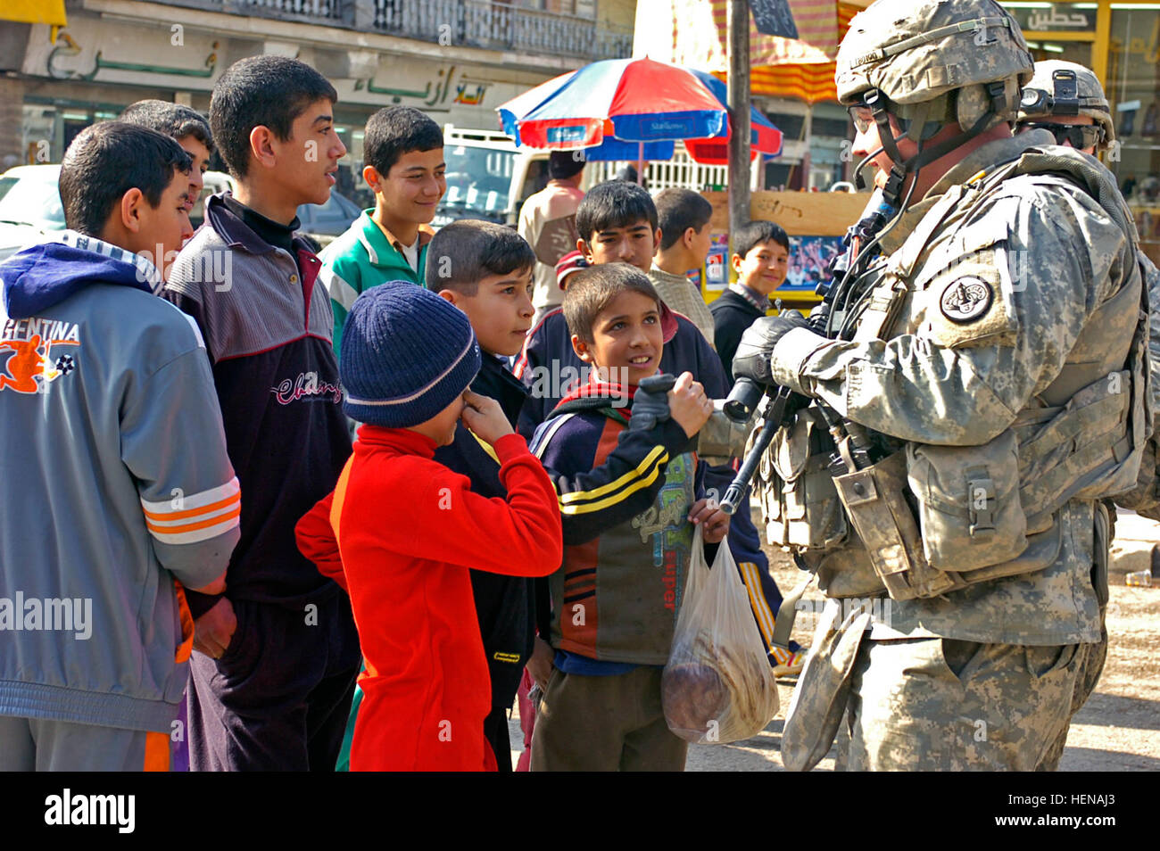 Staff Sgt. Thomas Bruhn, a cavalry scout in 3rd Platoon, Killer Troop, 3rd Squadron, 3rd Armored Cavalry Regiment from Fort Hood, Texas, shows an Iraqi boy how to 'shake up' like an American, while walking through the busy Al Dawasa market of Mosul, Iraq, Feb. 9. 3rd ACR visits a busy market in Mosul 76708 Stock Photo