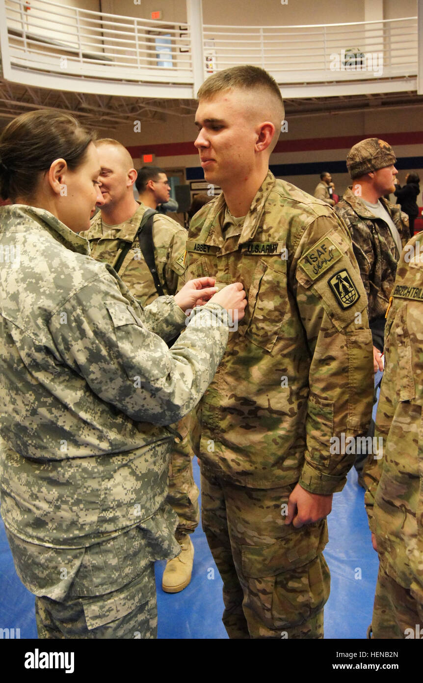 Pfc. Nathaniel Abbey, 57th Expeditionary Signal Battalion, 11th Signal Brigade, gets promoted to specialist and gets 'pinned' by his wife Jan. 28, 2014, minutes before the deployment ceremony begins. A deployment ceremony was held at the West Fort Hood Physical Fitness Center, and Abbey and three other soldiers were promoted to specialist before boarding a plane overseas in support of Operation Enduring Freedom. (U.S. Army Photo by Staff Sgt. Kelvin Ringold, 11th Signal Brigade PAO) %%%%%%%%E2%%%%%%%%80%%%%%%%%98Lightning Warriors%%%%%%%%E2%%%%%%%%80%%%%%%%%99 leave Fort Hood, deploy for missi Stock Photo