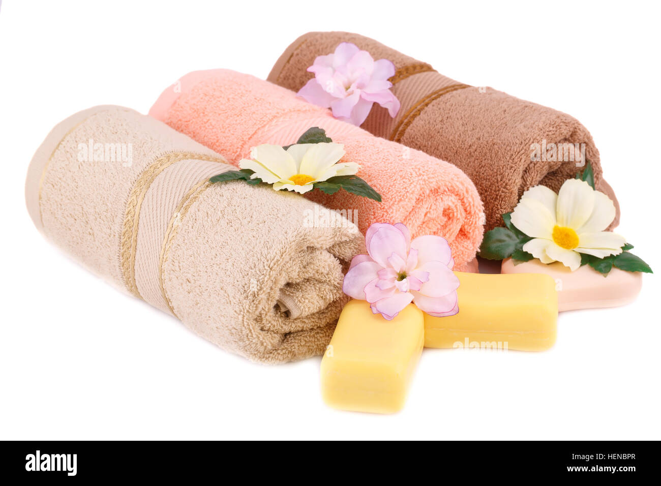 Rolled towels, soaps and flowers isolated on white background. Stock Photo