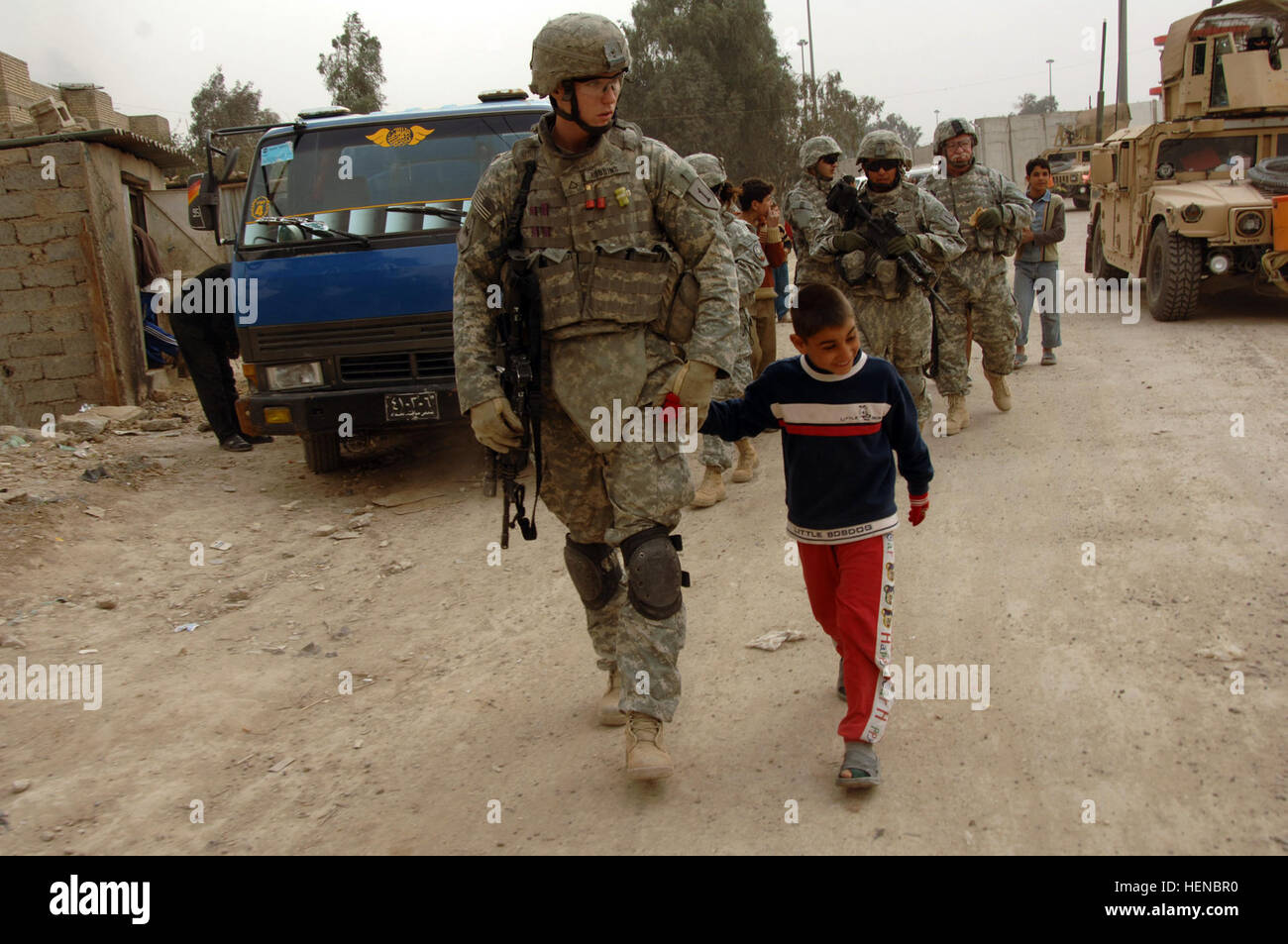 Pfc. Steven Robbins from Battery B, 2nd Battalion, 32nd Field Artillery Regiment, attached to 2nd Brigade Combat Team, 101st Airborne Division (Air Assault),  holds hands with an Iraqi boy during a patrol in Qadasiyah, Iraq, Feb. 18.  (U.S. Army photo/Sgt. Sharhonda R. McCoy) Dismounted Patrol 78186 Stock Photo