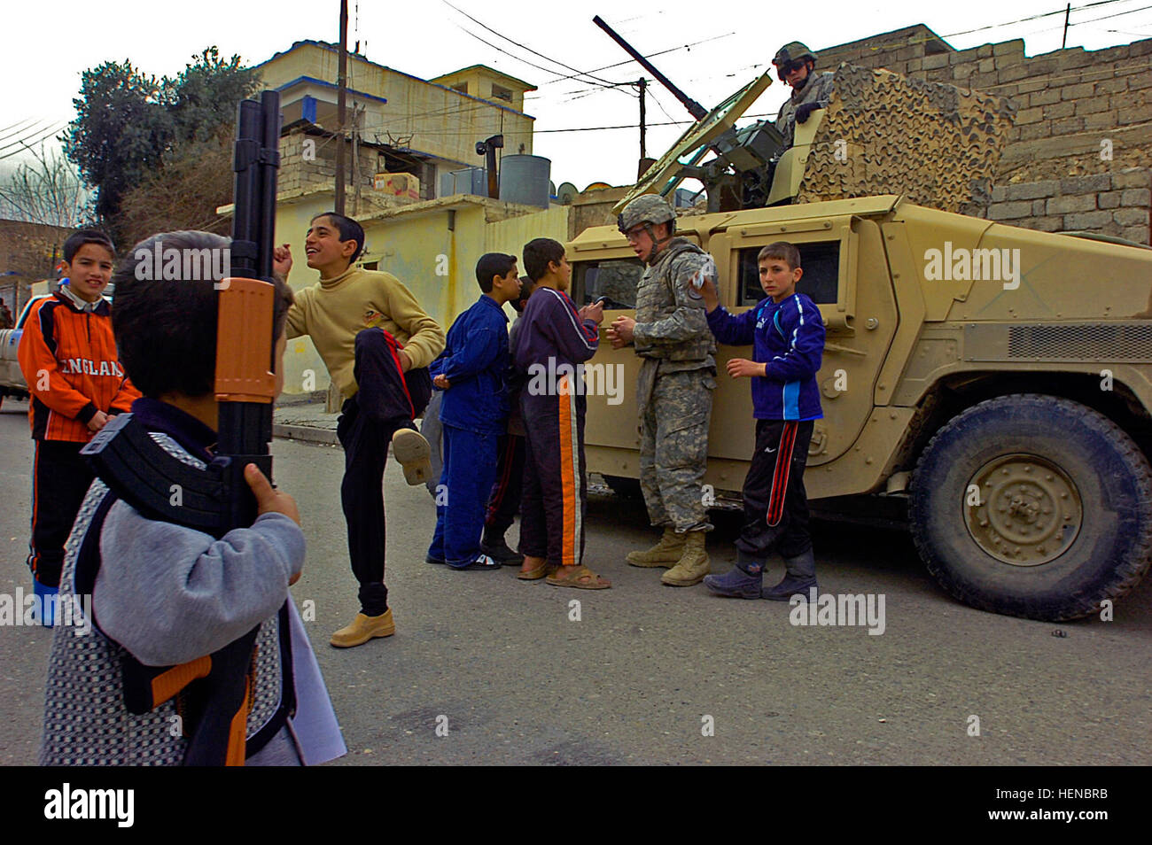 A young Iraqi boy holds his toy AK-47 as Soldiers of Killer Troop, 3rd Squadron, 3d Armored Cavalry Regiment from Fort Hood, Texas, talk to the local children while visiting a local Iraqi police station in Mosul, Iraq, Feb. 18. Soldiers show their friendly side to Iraqi children 77806 Stock Photo