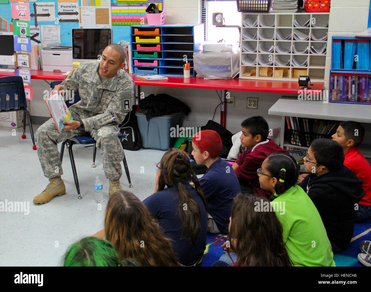 Staff Sgt. Alsherdan Lopez, a noncommissioned officer with the 402nd Field Artillery Brigade, reads the book 'Green Eggs and Ham' by Dr. Seuss to the students of Presa Elementary School, March 6 in El Paso, Texas. The school celebrated the Read Across America event all week and encouraged creativity with themed days. On March 5, the theme was wacky hair Wednesday, where students came to school with colored and styled hair like the characters in their favorite Dr. Seuss books. (Photo by 1st Lt. Vanessa Dudley, 1st Battalion, 361st Regiment, 5th Armored Brigade, Division West Public Affairs) 402 Stock Photo