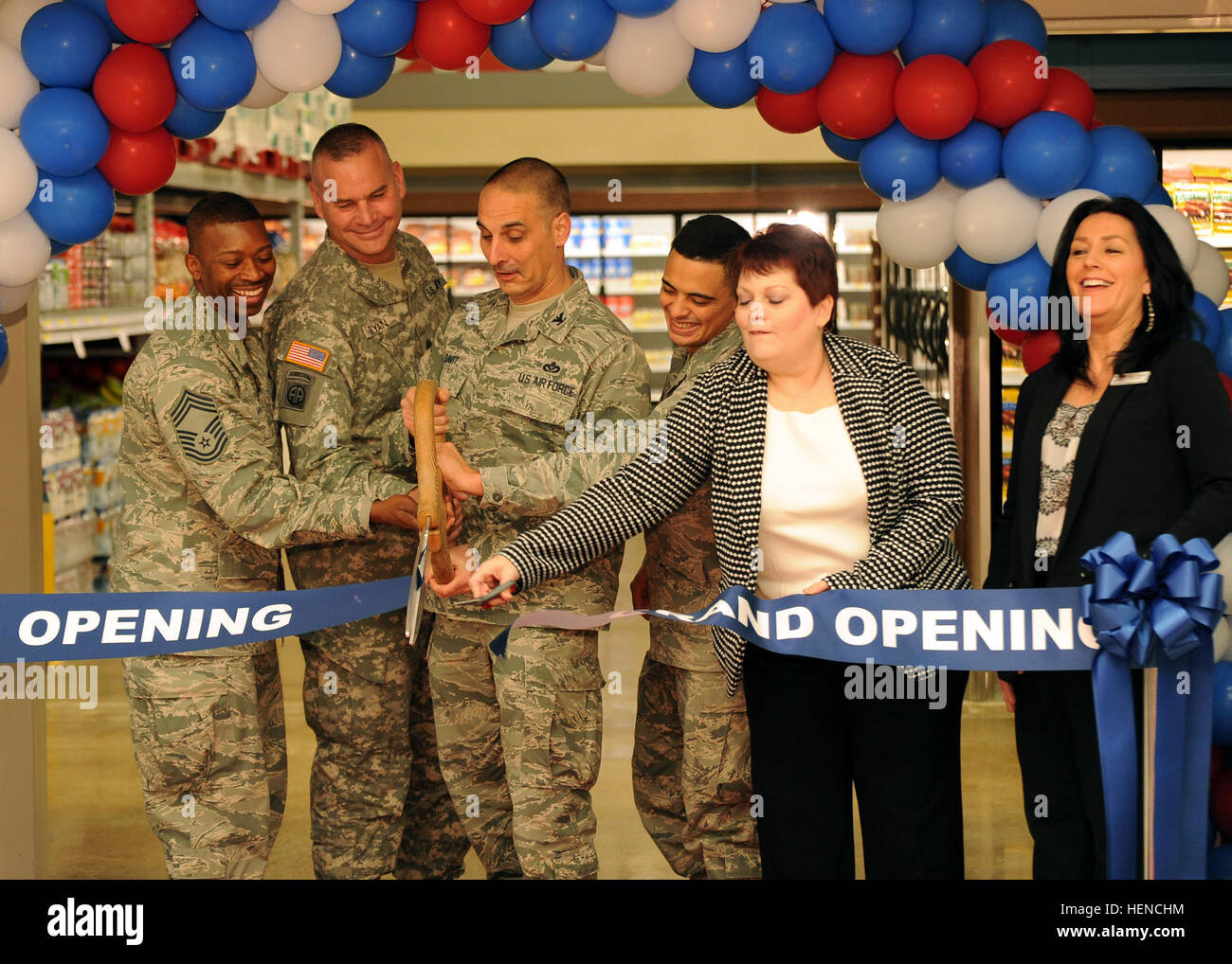 Victoria Best-Rush, DeCA Zone Manager, applies the finishing touch during the McChord Commissary Club Store Grand Opening Ribbon Cutting, with (L-R) CMSgt Anthony Woods, CSM Kevin Bryan, Col. Anthony Davit, Airman 1st Class Eric Deleon, and Janice Coleman, Store Director. Commissary Club Store Grand Opening 140307-A-PU960-005 Stock Photo
