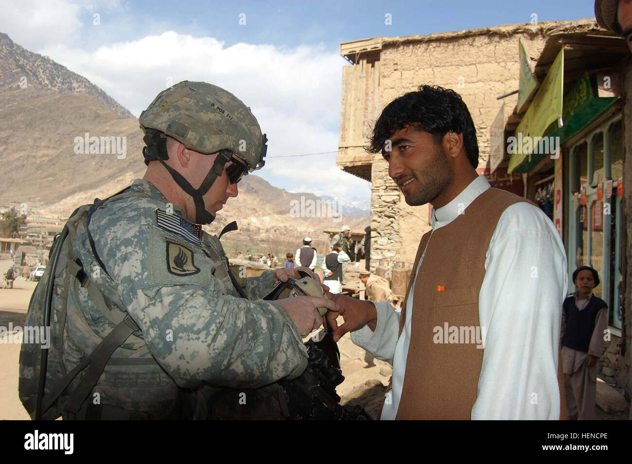 Army Pvt. Kevin Coons, 22, of Wichita, Kan., a forward observer with 1st Platoon, Chosen Company, 2nd Battalion, 503rd Infantry Regiment, scans a local shop owner's fingerprints using the Handheld Interagency Identity Detection Equipment System during a presence patrol Feb. 24 to the village of Nangalam, Kunar province, Afghanistan. Chosen Company Maintains Presence in Nangalam 79934 Stock Photo