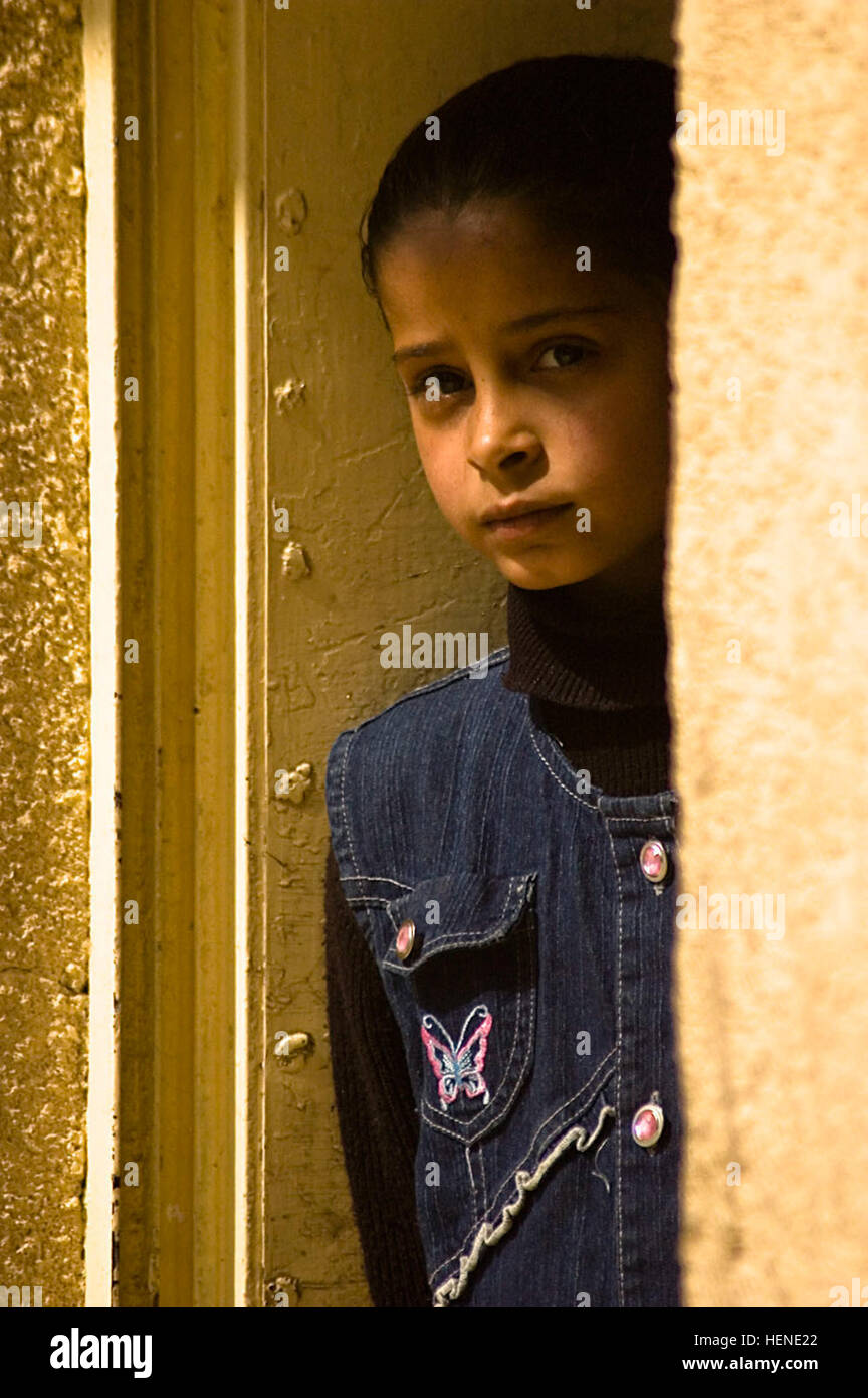 An Iraqi student peeks out from around the corner to catch a view of Soldiers from the 411th Military Police Company, 716th MP Battalion, 18th MP Brigade, Multi-National Division – Baghdad as they stand guard outside her elementary school in the village of Abayachi, north of Baghdad, March 2. Soldiers from the 411th MP Co. supported the mission of Company B, 1st Battalion, 14th Infantry Regiment, 2nd Stryker Brigade Combat Team, “Warrior,” 25th Infantry Division, MND-B to pay local Sons of Iraq (Abna al Iraq) volunteers from the Abayachi area. Soldiers support payday activities 79516 Stock Photo