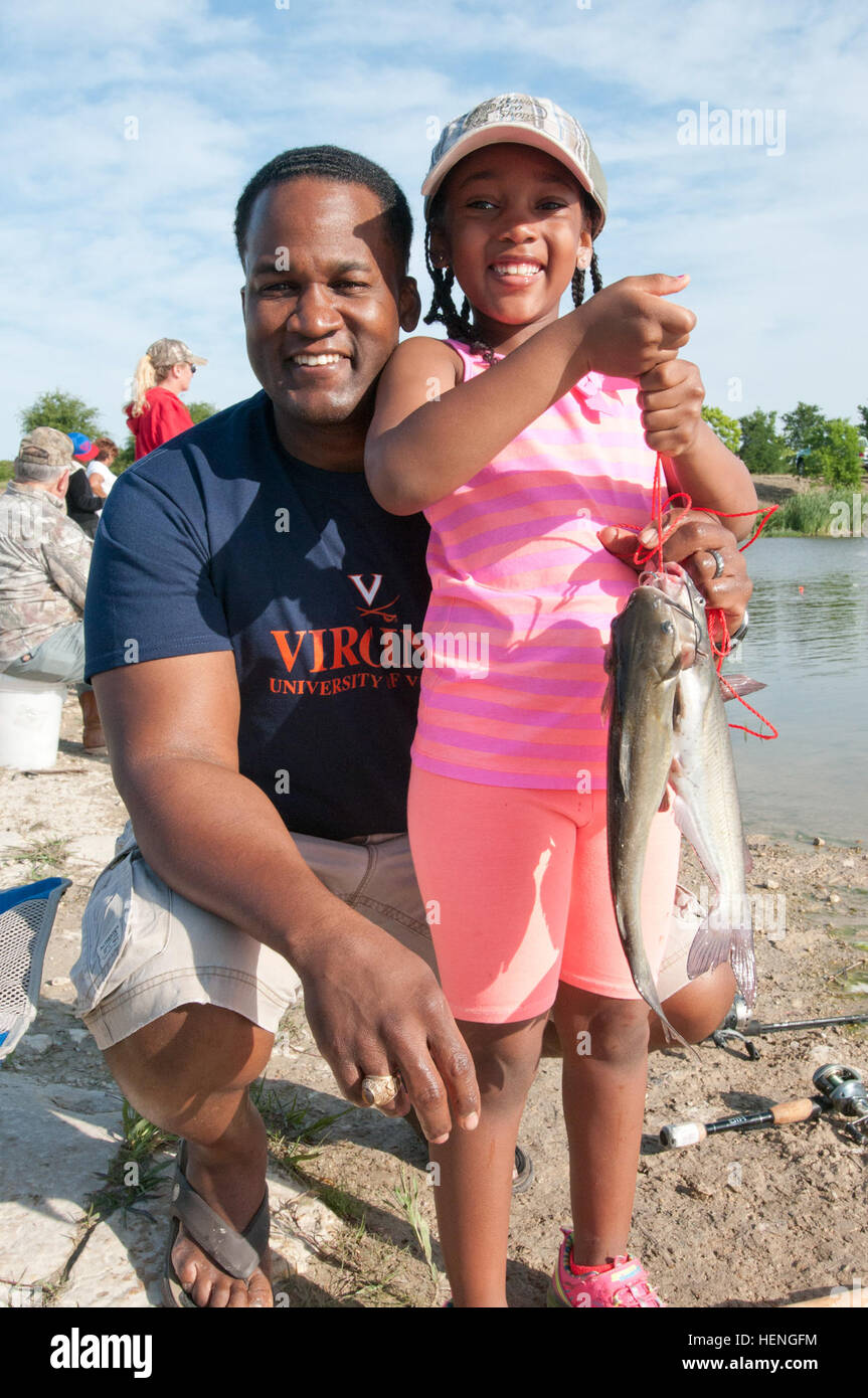 Kevin Green, an auditor at the III Corps and Fort Hood Internal Review Directorate, alongside his 7-year-old daughter Chloe proudly display their second catch of the day at the Family Fishing Clinic held by the Sportsmen Center at Fort Hoods Cantonment B pond, 17 May 2014. The Family Fishing Clinic taught families who were unfamiliar with the finer points of fishing everything they needed to know in order to catch and clean fish as well as providing fishing veterans an opportunity to hone their skills and bring their families into the sport. (U.S. Army photo by Sgt. John Healy, 7th Mobile Publ Stock Photo