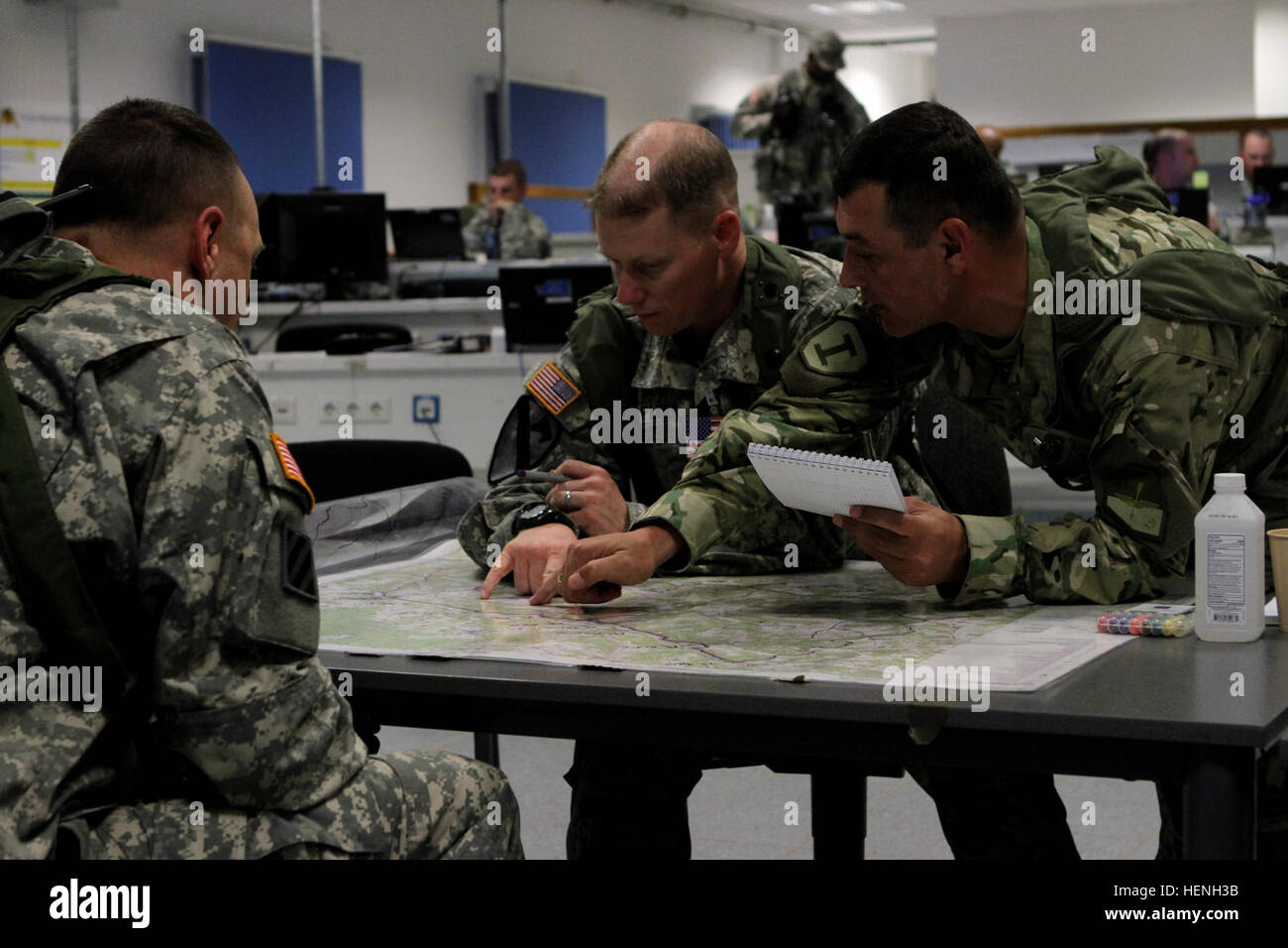 Maj. Eric Melloh, left, the 1st Brigade Combat Team, 1st Cavalry Division operations officer, Capt. Micah Chapman, middle, the 1st BCT operations planner and Maj. Grigolia, right, the 1st Georgian Infantry Brigade operations planner, discuss troop movements in the 1st BCT tactical operations center at Hohenfels Training Area during the multi-national training event, Combined Resolve II. Planning on the map 140523-A-SJ786-009 Stock Photo
