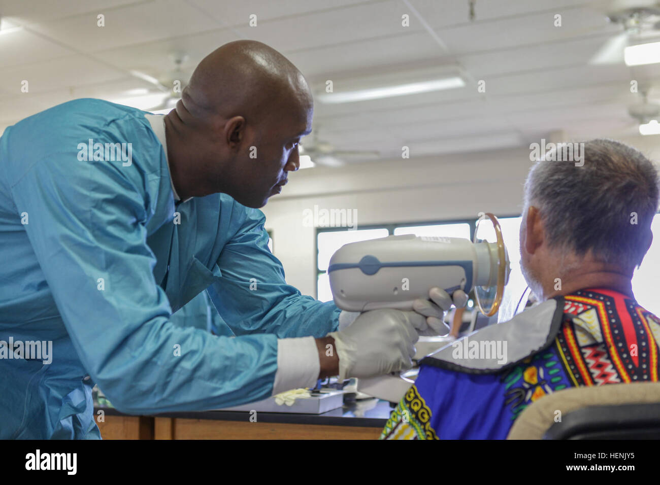 US Army Sergeant Yves Lorthe, with the 455th Medical Company (Dental Services) out of Devens, MA, scans a local patient with a hand held x-ray machine during Tropic Care 2014, Kapa'a Hawai'i, June 17, 2014. Tropic Care 2014 is an Innovative Readiness Training exercise that provides real world training in a joint civil and military environment while delivering world class medical care to the people of Kaua'i (U.S. Army photo by SPC Cory Long/Released) Tropic Care 2014 140617-A-BM801-012 Stock Photo