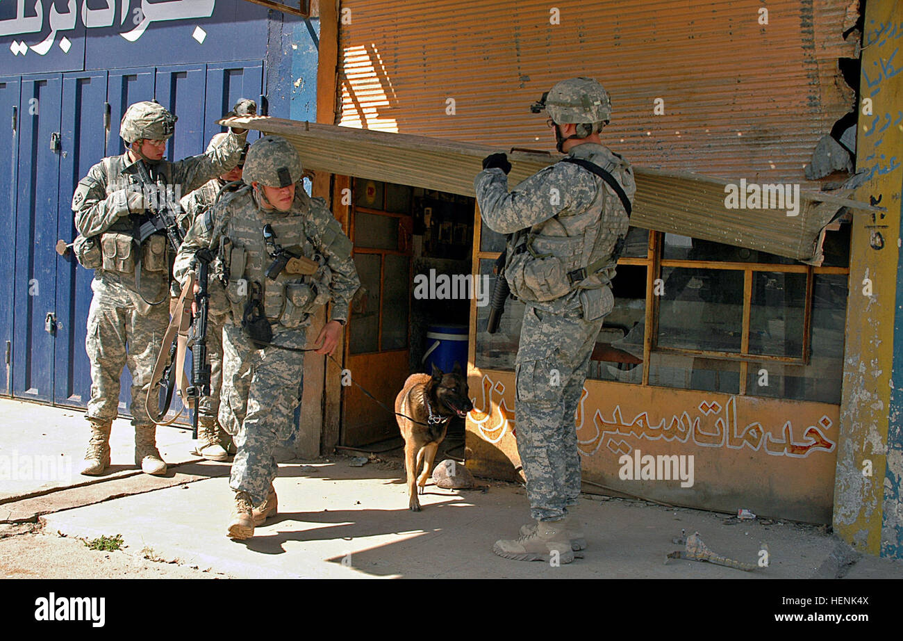 Soldiers of 1st Platoon, Company D, 1st Battalion, 8th Infantry Regiment from Fort Carson, Colo., lift a door for Petty Officer 3rd Class Josh Raymond and his military police dog after searching the building for explosives during a clearing operation in Mosul, Iraq, April 1. Iraqi Army Division led raid on Mosul neighborhood finds car bomb factory 83275 Stock Photo