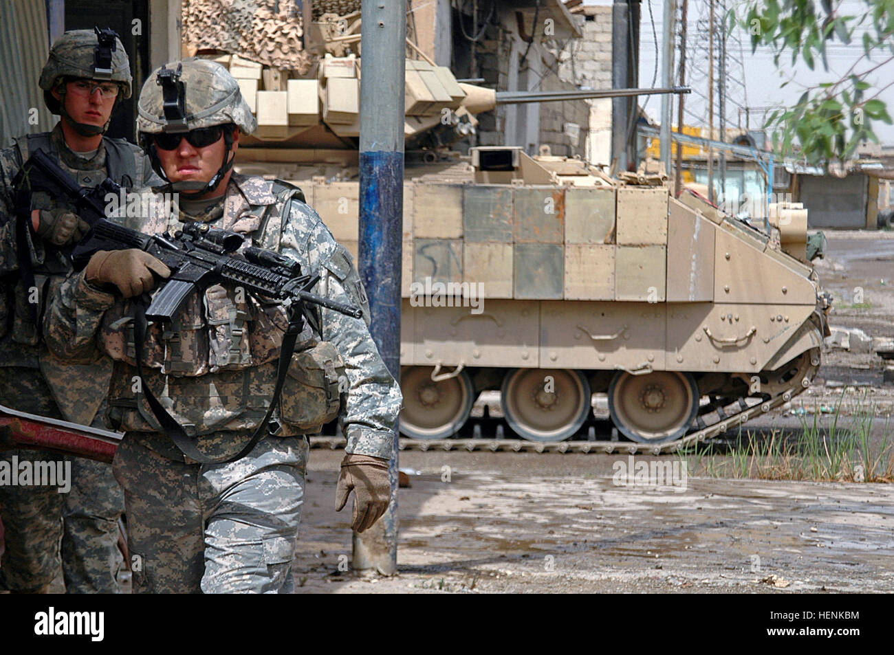 Spc. Jimmy Marble (front) and Pfc. Adam Devries move through the streets of Mosul during a clearing operation as a Bradley Armored Personnel Carrier rolls by providing security for the dismounted Soldiers. Both Soldiers are in 1st Platoon, Co. D, 8th Infantry Regiment from Fort Carson, Colo. Iraqi Army clears Mosul neighborhood after car bombs on combat outposts 83263 Stock Photo