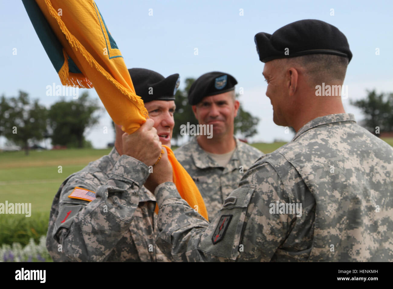 Maj. Gen. Paul E. Funk, commanding general of 1st Infantry Division out of Fort Riley, Kan., receives the 4th Maneuver Enhancement Brigade colors from outgoing commander Col. James F. Reckard III as incoming commander Col. Antonio 'Andy' Munera looks on, during a change of command ceremony held at Gammon Field, June 25, 2014. Passing of the colors is passed from the standing commander through the senior commander of that organization and is symbolic of the responsibility and all other assumptions for the welfare and success of the unit. (Photo by U.S. Army Staff Sgt. Kelly S. Malone, 4th Maneu Stock Photo