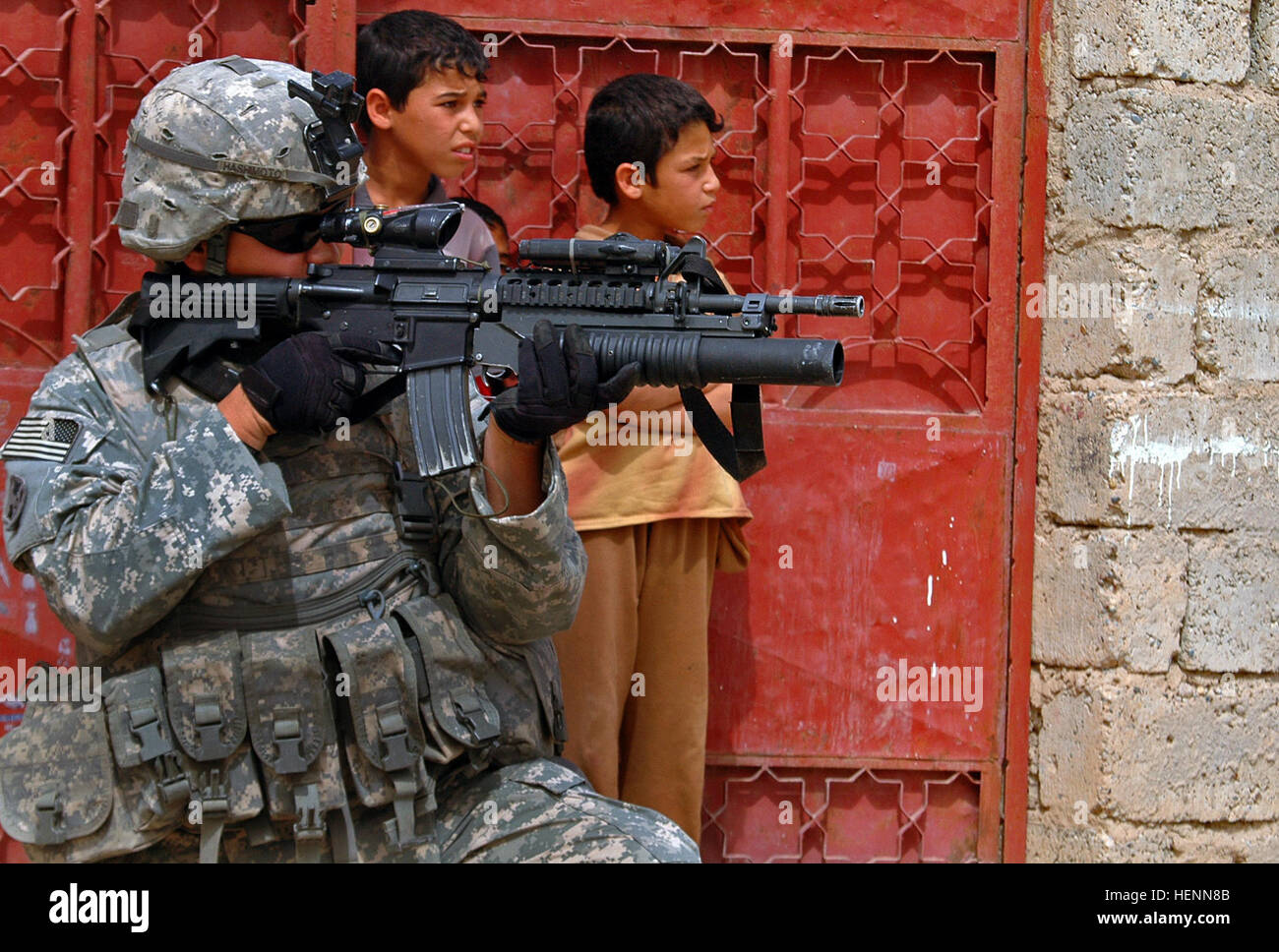 As Iraqi children peek out their front gate Spc. Vencent Hashimoto, an infantryman in 1st Platoon, Company D, 1st Battalion, 8th Infantry Regiment from Fort Carson, Colo., scans his surroundings during a combat patrol in  Mosul, Iraq, on April 12. Infantry Soldiers recon Mosul 84770 Stock Photo