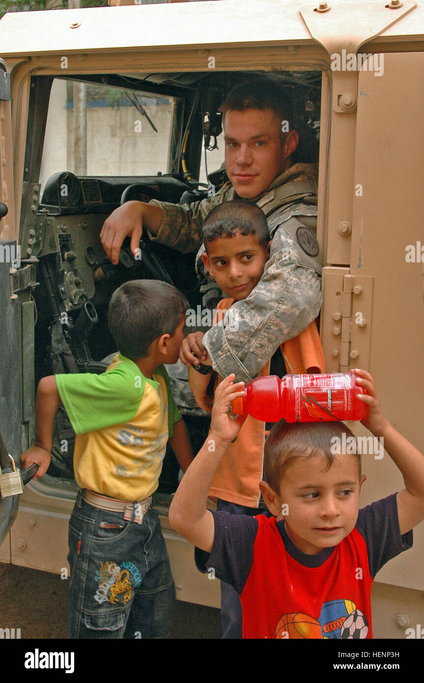 Spc. Robert Hubbard poses for a picture with Iraqi children outside an Iraqi police station in West Mosul, Iraq, on April 16. Soldiers passed out Gatorade and water to the children. Hubbard is in 1st Platoon, Killer Troop, 3rd Squadron, 3rd Armored Cavalry Regiment from Fort Hood, Texas. Killer Troop shows softer side to Iraqi children, Mosul 84779 Stock Photo