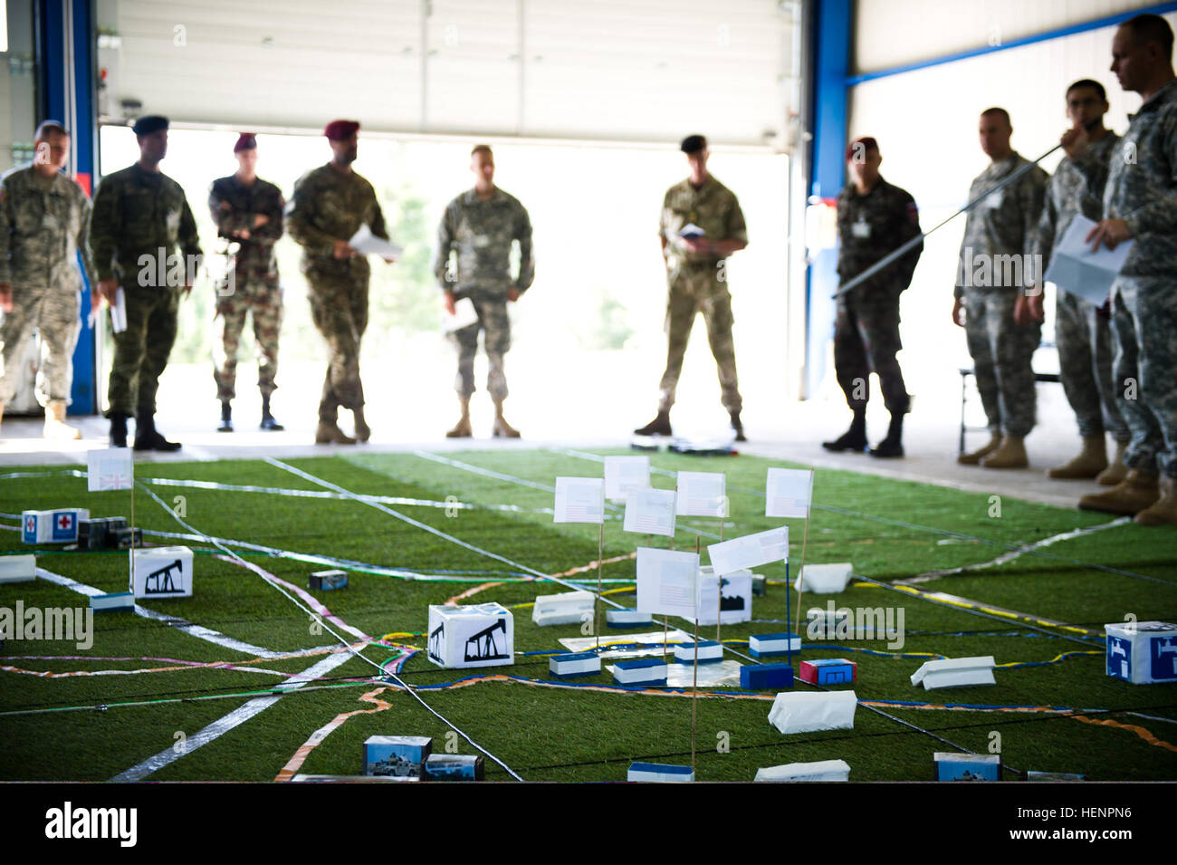 U.S. Soldiers and foreign service members gather around a large-scale sandtable to track troop movement on a simulated regional crisis map Aug. 25, 2014, in Postojna, Slovenia, during Immediate Response 14. Immediate Response is a U.S. Army Europe-led combined joint tactical field training exercise designed to build interoperability between NATO, Croatia and its regional partner nations. (U.S. Army photo by Staff Sgt. Caleb Barrieau/Released) U.S. Soldiers and foreign service members gather around a large-scale sandtable to track troop movement on a simulated regional crisis map Aug. 25, 2014, Stock Photo