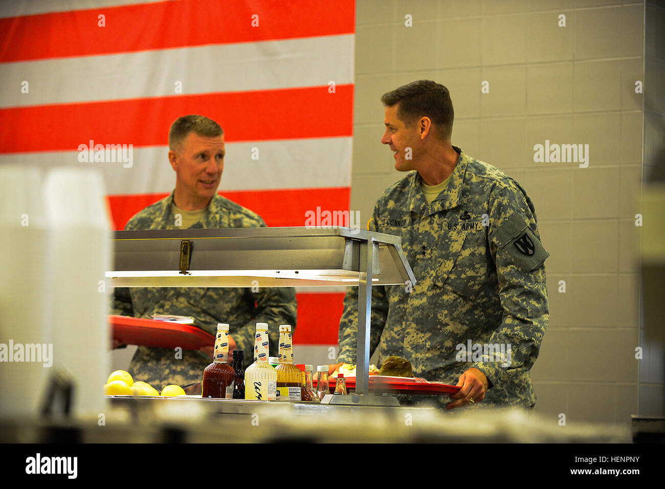 Maj. Gen. John R. O'Connor (right), commanding general of the 21st Theater Sustainment Command, and Col. Dave Brown, outgoing Mihail Kogalniceanu Air Base Regional Support Element officer-in-charge, prepare to eat lunch with military and civilian personnel serving at MK during a visit of the transient air base conducted Aug. 26. The visit provided O’Connor an opportunity to welcome the new RSE OIC, Col. Kevin Mulvihill, and gain insight while providing direction on current and future operations of the base. In February 2014, MK Air Base assumed the bulk of the passenger transit mission for Sol Stock Photo