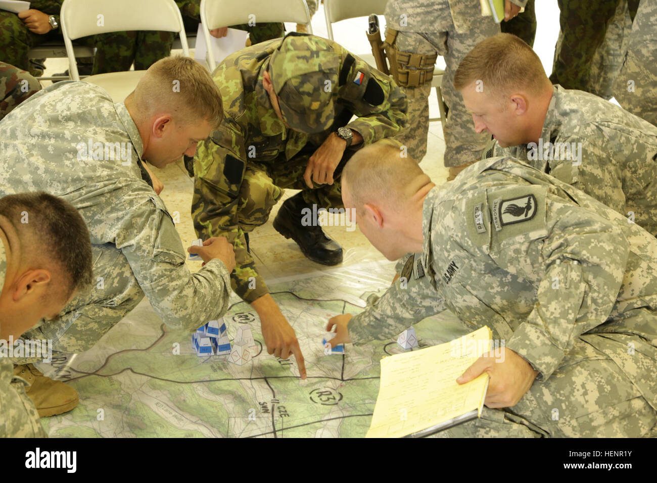 U.S. Soldiers of 1st Battalion, 503rd Infantry Regiment, 173rd Airborne Brigade and a Czech soldier place unit tokens on a map during training exercise Saber Junction 2014 at the Joint Multinational Readiness Center in Hohenfels, Germany, Aug. 30, 2014. Saber Junction 2014 prepares U.S., NATO allies and European security partners to conduct unified land operations through the simultaneous combination of offensive, defensive and stability operations appropriate to the mission and the environment. More information about Saber Junction 2014 can be found at http://www.eur.army.mil/SaberJunction/.  Stock Photo