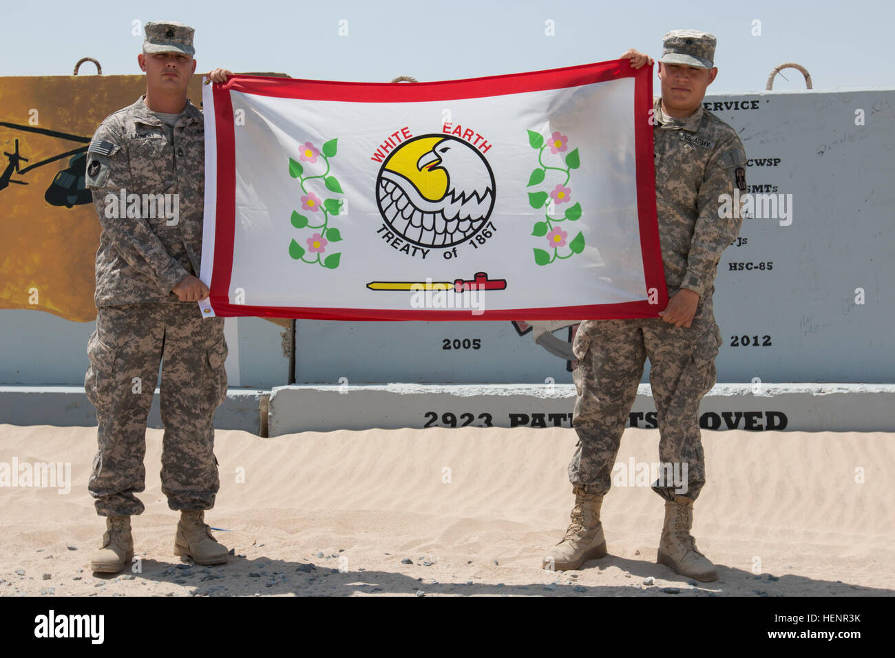 From left: Sgt. 1st Class Laudert, an intelligence analyst with the 34th Combat Aviation Brigade of the Minnesota National Guard and his brother, Spc. Cameron Laudert, a health care specialist with the 452nd Combat Support Hospital, U.S. Army Reserve, show their respect for their Native American heritage, displaying the White Earth Nation flag. They are deployed to Camp Buerhing in support of Operation Enduring Freedom-Kuwait. (Minnesota Army National Guard photo by 1st Lt. Holly Elkin/Released) Minnesota brothers reunite in Kuwait 140901-A-QD498-852 Stock Photo