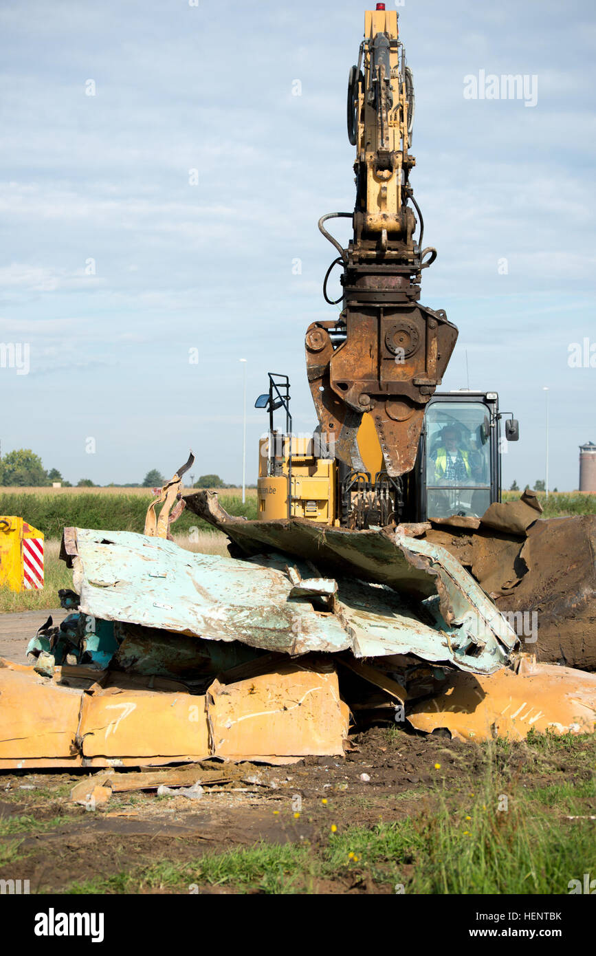 View of the 5000+ PSI demolition shear jaws of a tracked hydraulic excavator tearing apart decommissioned jet fuel tanks in order to ship and recycle them on Chièvres Air Base, Belgium, Sept. 18, 2014. (U.S. Army photo by Visual Information Specialist Pierre-Etienne Courtejoie-Released) POL tanks demolition and recycling 140918-A-BD610-057 Stock Photo