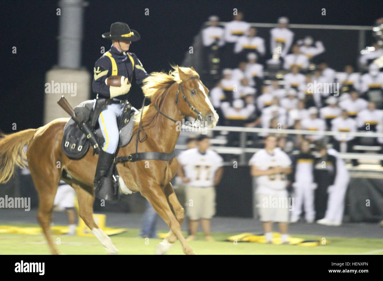 Sgt. Jessie Hurst, a Trooper with the U.S. Army’s 1st Cavalry Division Horse Detachment, delivers the game ball while riding “Hammer” in front of more than 500 attendees during a high school football game at Burnet, Texas, Oct. 24. Prior to kickoff, the 1st Air Cavalry Brigade, 1st Cav. Div.’s leadership was recognized for their community partnership with the city of Burnet, and the 1st Cav. Div. Horse Detachment presented the national colors. First Team honored during high school football game 141024-A-WD324-044 Stock Photo