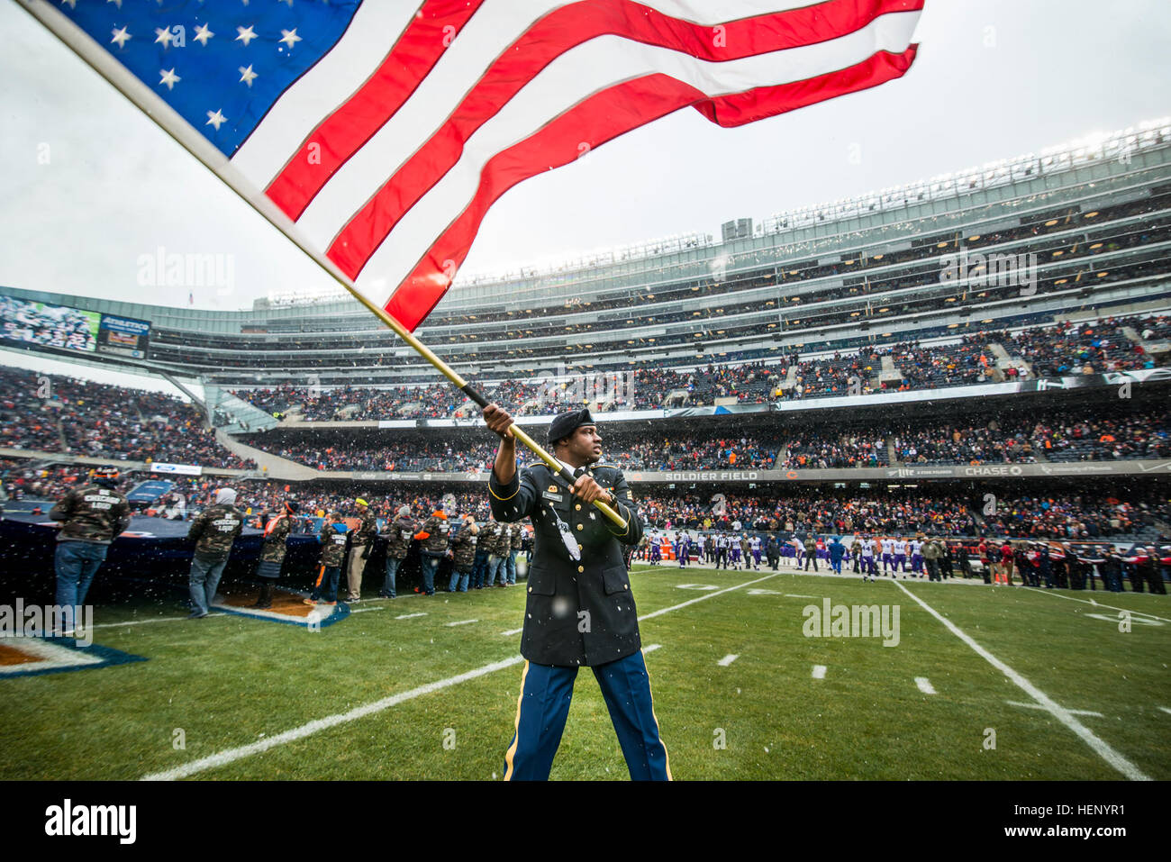 Sgt. Brian Abrams, Army Reserve Soldier with the 863rd Engineer Battalion, Forward Support Company, waves the American flag on the field after leading the Chicago Bears team members prior to kickoff during an NFL game designated to honor veterans and military service members at Soldier Field in Chicago, Nov. 16. (U.S. Army photo by Sgt. 1st Class Michel Sauret) Military service members honored during Chicago Bears game 141116-A-TI382-323 Stock Photo