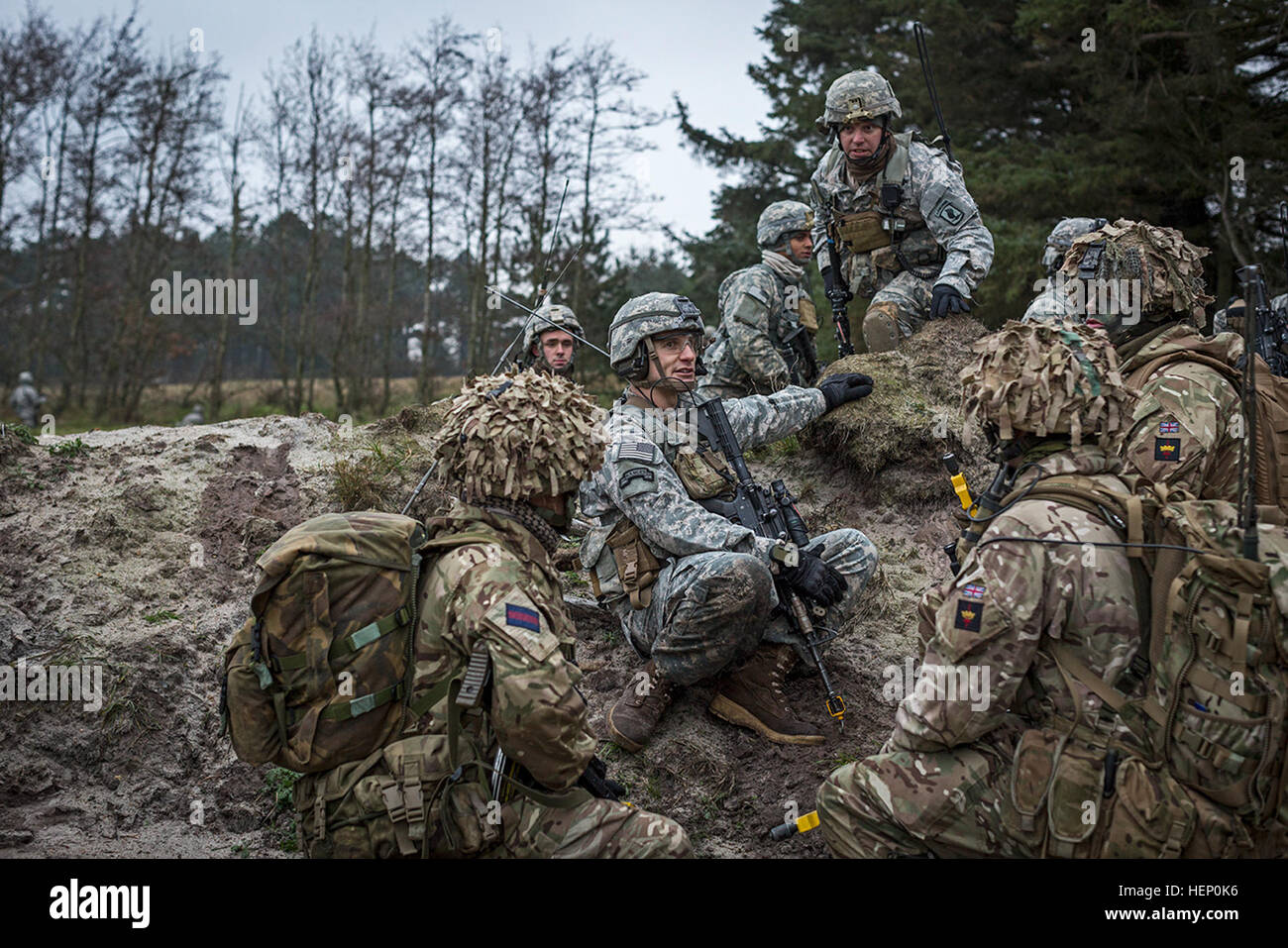 U.S. Army Capt. Nicolas Salimbene (seated, center), commander of Company B, 1st Battalion, 503rd Infantry Regiment, 173rd Airborne Brigade, directs British soldiers from Queens Company, Grenadier Guards where to attack the opposing force during Exercise White Sword here, Dec. 3, 2014. Exercise White Sword is a multinational exercise involving over 1,500 NATO troops from Denmark, U.K. and the U.S., and designed increase interoperability between allied forces and certify the Danish 2nd Brigade RBG for the 2015 NATO Reaction Force. (U.S. Army photo by Sgt. Benjamin John) Exercise White Sword 1412 Stock Photo