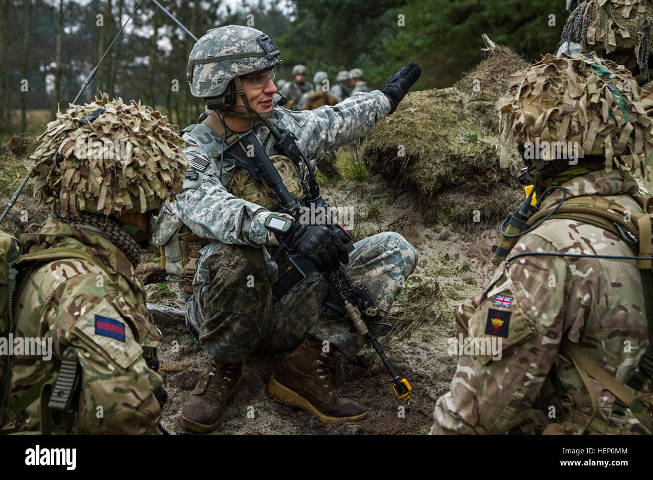 U.S. Army Capt. Nicolas Salimbene, commander of Company B, 1st Battalion, 503rd Infantry Regiment, 173rd Airborne Brigade, directs British soldiers from Queens Company, Grenadier Guards, where to attack the opposing force during Exercise White Sword here, Dec. 3, 2014. Exercise White Sword is a multinational exercise involving over 1,500 NATO troops from Denmark, U.K. and the U.S., and designed increase interoperability between allied forces and certify the Danish 2nd Brigade RBG for the 2015 NATO Reaction Force. (U.S. Army Photo by Sgt. Benjamin John) Exercise White Sword 141204-A-DS355-163 Stock Photo