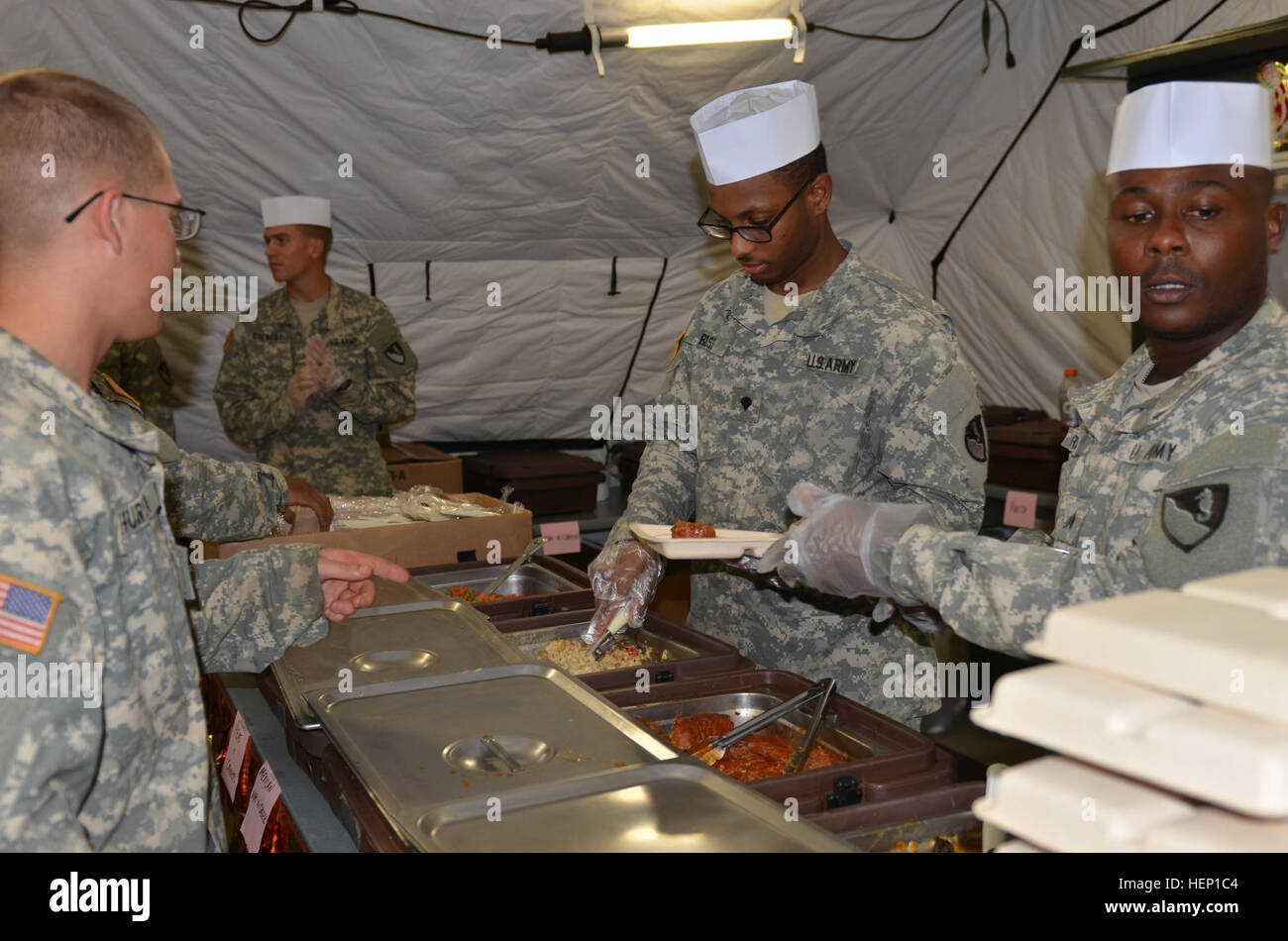 From left, Spc. Benjamin Ross, a Chicago native and food service specialist, and Sgt. William Burrell, right, the noncommissioned officer in charge of rations and a native of Union, Ala., both of Forward Support Company, 62nd Battalion, 36th Engineer, serves Soldiers food at the National Police Training Academy, Monrovia Paynesville, Liberia, during the Operation United Assistance mission Dec. 15, 2014. Operation United Assistance is a Department of Defense operation in Liberia to provide logistics, training and engineering support to U.S. Agency for International Development-led efforts to co Stock Photo