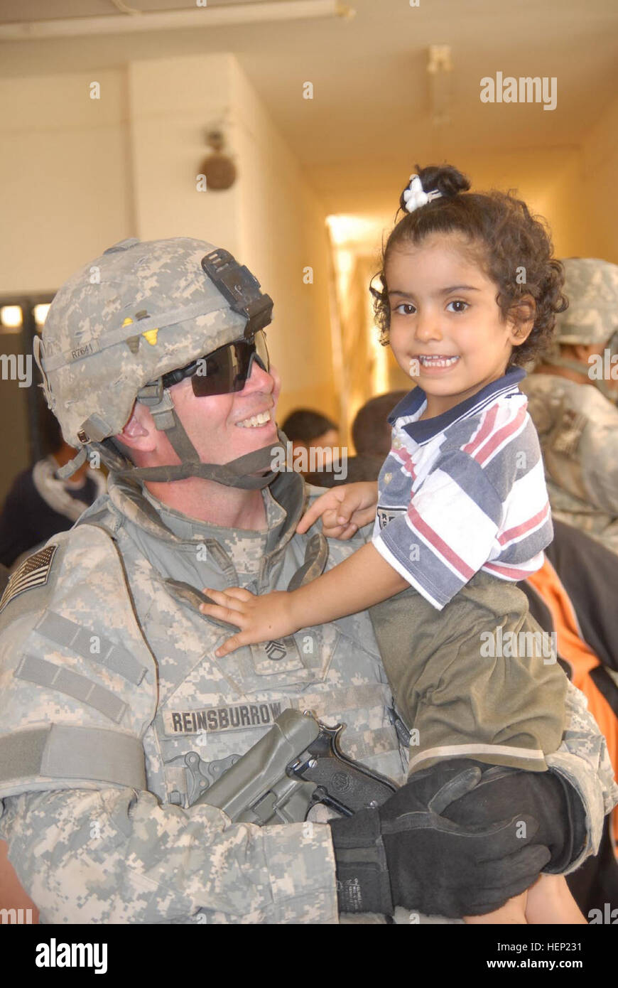 Staff Sgt. Joseph Reinsburrow, 64th Military Police Company and native of Towanda, Pa., holds an Iraqi child on June 12 in Hurriyah, while Iraqi police and coalition forces hand out toys and school supplies to the local children. The 64th MP Co., is deployed from Fort Hood, Texas, and is currently assigned to the 716th MP Battalion, 18th MP Bde., MND-B. IP making difference in local Baghdad community 94492 Stock Photo