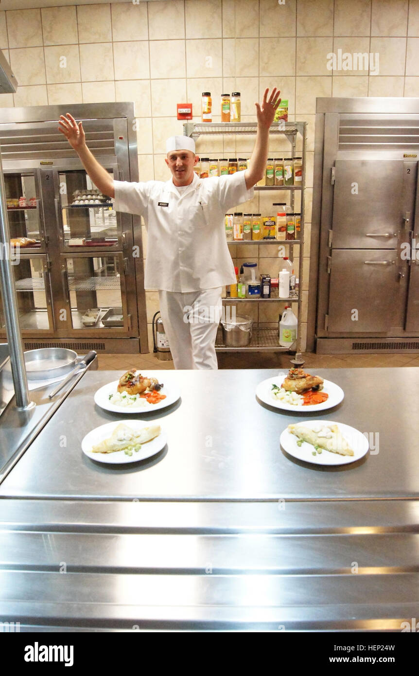 After hearing a grader yell 'hands up,' Sgt. Kory Bender, Alpha Company, 40th Expeditionary Signal Battalion, 11th Signal Brigade, throws his hands up and steps away from his dishes. During the Culinary Arts Noncommissioned Officer of the Year board at Fort Hood, Texas, Jan. 8–9, Soldiers needed to have completed plating their meals and have them ready for presentation when that command was given. (U.S. Army Photo by Staff Sgt. Kelvin Ringold) Sergeant cooks up a win at Culinary Arts of Quarter board 150109-A-HT688-316 Stock Photo