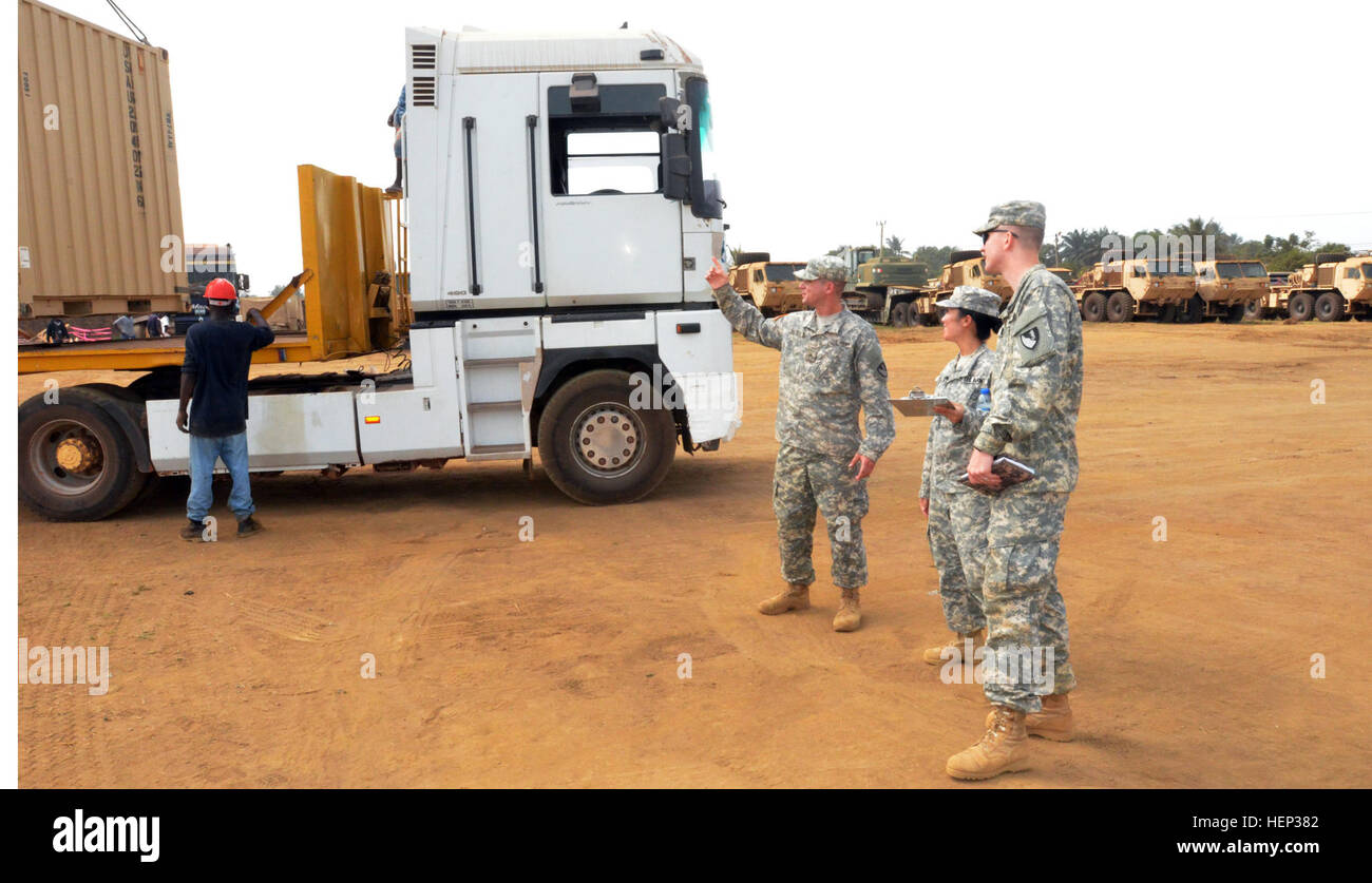 Cpl. James Lembke, left, a West Seneca, N.Y., native and a heavy equipment operator for the Headquarters and Headquarters Company, 62nd Engineer Battalion, 36th Engineer Brigade, briefs 1st Lt. Priscilla Ro, center, Valencia, California, native and a unit movement officer for HHC, 62nd Eng. Bn., 36th Eng. Bde, on the number of containers that are going on each of the non-tactical vehicles in support of Operation United Assistance, Joint Forces Command – United Assistance, at the National Police Training Academy, Paynesville, Liberia, Jan. 15, 2015. Lembke is a safety specialist for the contain Stock Photo