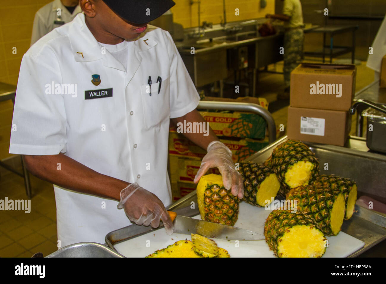 A Soldier who works at the Talon Cafe cuts a fresh pineapple for the Salad bar Jan. 23, 2015 at a dining facility on Camp Humphreys. Fueling Soldiers 150122-A-TU438-163 Stock Photo