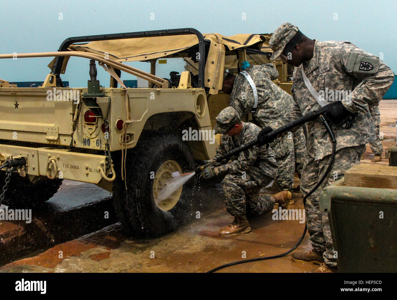 Staff Sgt. Terrance Daniels, right, sprays down a vehicle with a pressure washer while Spc. Kolton Price, center, native of Winfield, Kan., and Sgt. Andrea Jackson, left, native of Houston, scrub and clean a vehicle at the United States Department of Agriculture inspection point, Camp Buchanan, Liberia, Jan. 23, 2015. All Soldiers are part of the 53rd Movement Control Battalion, 101st Sustainment Brigade, deployed as Task Force Lifeliner in support of Joint Forces Command – United Assistance, who help operate the USDA inspection point, ensuring all vehicles and equipment headed back to the U.S Stock Photo