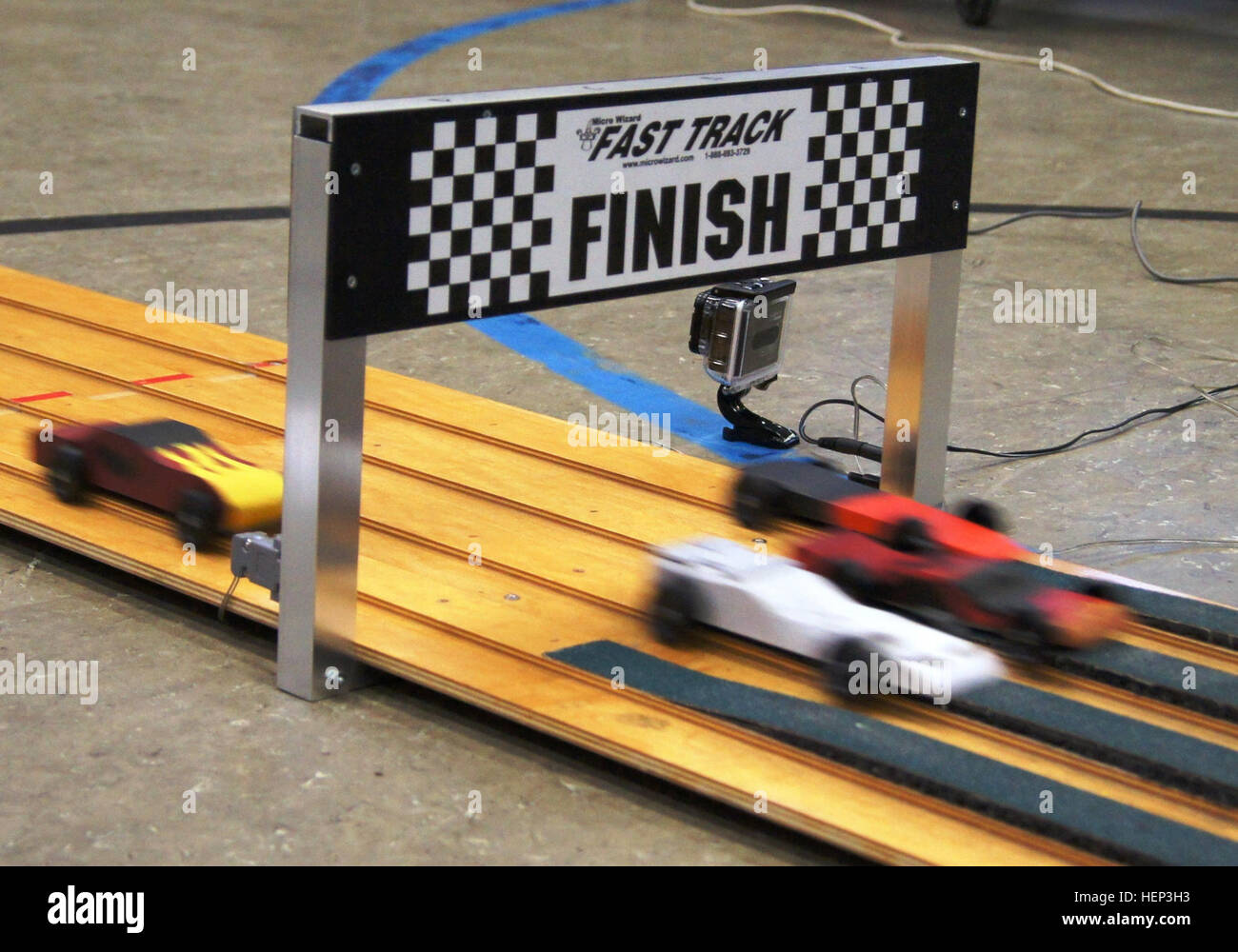 Sleek Scout sports cars cross the finish line simultaneously during the Pack 69 Pinewood Derby conducted Jan. 24 at Vogelweh Elementary School. Some 58 cars competed during the annual Scout racing extravaganza. Siblings, parents and adult volunteers as well as Scouts designed, cut and decorated wooden cars for the competition. (Photo by Samantha Spaulding, Pack 69) Scouts, families triumph in year's 'funnest' event 150124-A-XX000-002 Stock Photo