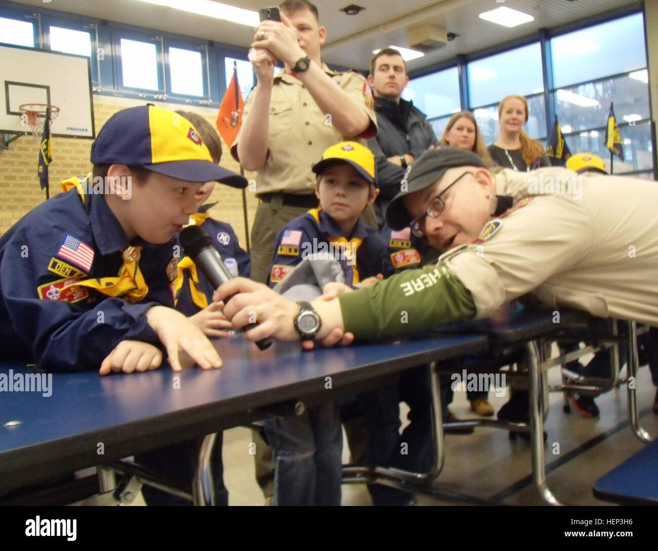 Maj. Michael J. Swienton, the Pack 69 cubmaster, or senior pack leader, “interviews” Wolf Scout Allen Jarvis from the “pit” during the Pack 69 Pinewood Derby held Jan. 24 at Vogelweh Elementary School. In addition to his administrative roles, the versatile Wisconsin native served as emcee and “roving reporter,” conducting “Laugh Olympics”-style question-and-answer sessions to inspire analysis, constructive thought and presentation skills between heats. Some Scouts attributed their success to advanced aerodynamics or interstellar inspiration while others candidly acknowledged their parents’ rol Stock Photo