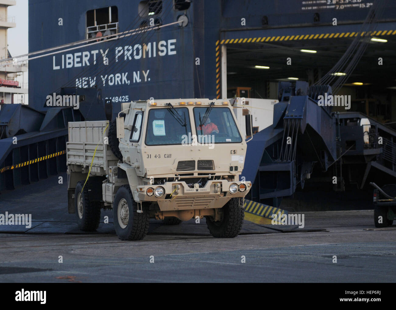 International logisticians offload a U.S. troop transport vehicle from the transportation vessel “Liberty Promise” March 13 at the Port of Bremerhaven. More than 300 pieces of equipment, including UH-60 Black Hawk helicopters, tracked vehicles, Humvees, troop carriers and assorted military cargo, will move onto sites in Latvia, Estonia and Lithuania in support of Operation Atlantic Resolve, an ongoing mission designed to exemplify U.S. and NATO commitment to the region, build allied capability and interoperability, and bolster regional security and stability. Soldiers of the 1st Armor Brigade  Stock Photo