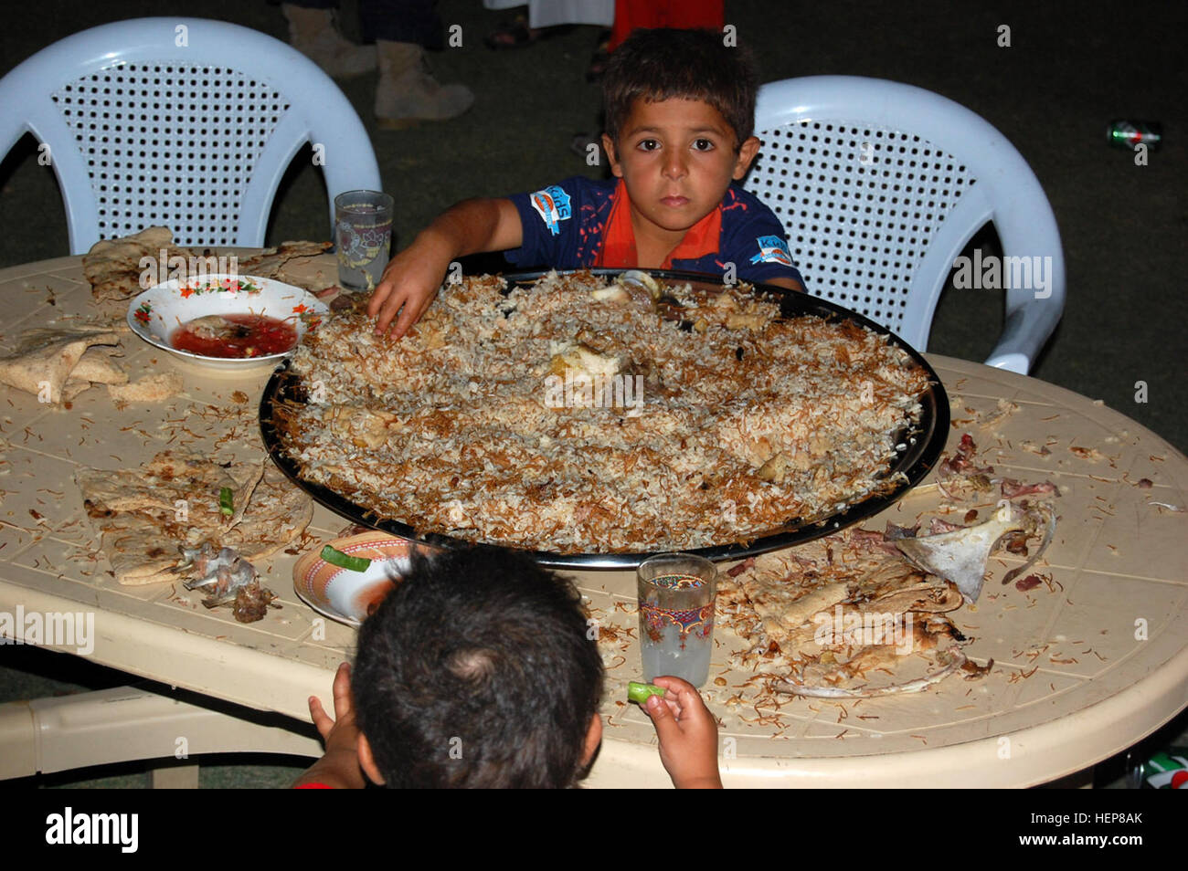 Camp Taji Iraq A Young Boy Digs In To A Large Tray Of Food During Stock Photo Alamy