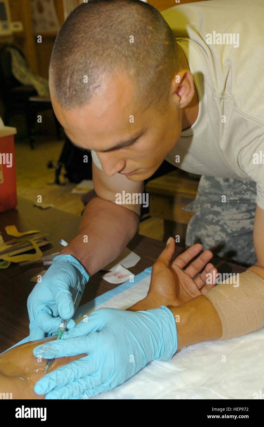 GUANTANAMO BAY, Cuba – Army Spc. Jerad Harper, a member of the 193rd Military Police Company here, practices starting an intravenous injection on fellow Joint Task Force Guantanamo Trooper, Spc. Henry Richardson, during a Combat Lifesavers course here, July 17, 2008.  Harper and other members of the 193rd received hands-on training guided by the bases only CLS-certified instructor, Staff Sgt. Christopher Ellis. JTF Guantanamo conducts safe and humane care and custody of detained enemy combatants. The JTF conducts interrogation operations to collect strategic intelligence in support of the Glob Stock Photo