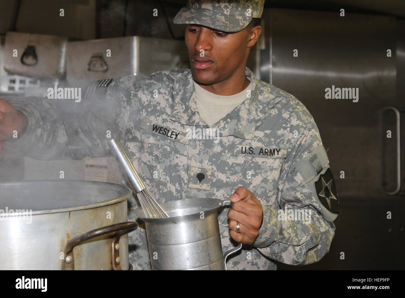 Spc. Brandon Wesley, a food service specialist with the Co. E, 3rd General Support Aviation Battalion, 2nd Combat Aviation Brigade pours water into a container April 1 just outside of Camp Humphreys in South Korea. The water was used to make chicken gravy which was part of a full lunch menu served to the judges of the Philip A. Connelly Award for Excellence in Army Food Services. Rising to the top 040115-A-TU438-003 Stock Photo
