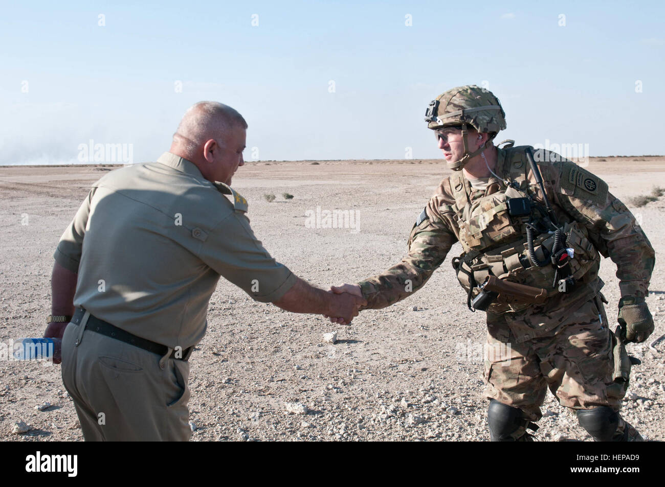 Brig. Gen. Hassan Mohamed Zieer, commander of Iraq’s Bomb Disposal School, (left) and Maj. Robert Tracy, executive officer of the 2nd Battalion, 505th Parachute Infantry Regiment, 3rd Brigade Combat Team, 82nd Airborne Division, shake hands after observing a successful d breaching operation at Besmaya Range Complex, Iraq, April 14, 2015. Sappers with the 2-505th PIR and members of the U.S. explosive ordinance disposal team demolished concrete barriers in preparation for a breaching class with Iraqi army soldiers of the 16th Division. (Photo by Sgt. Deja Borden, CJTF-OIR Public Affairs) Buildin Stock Photo
