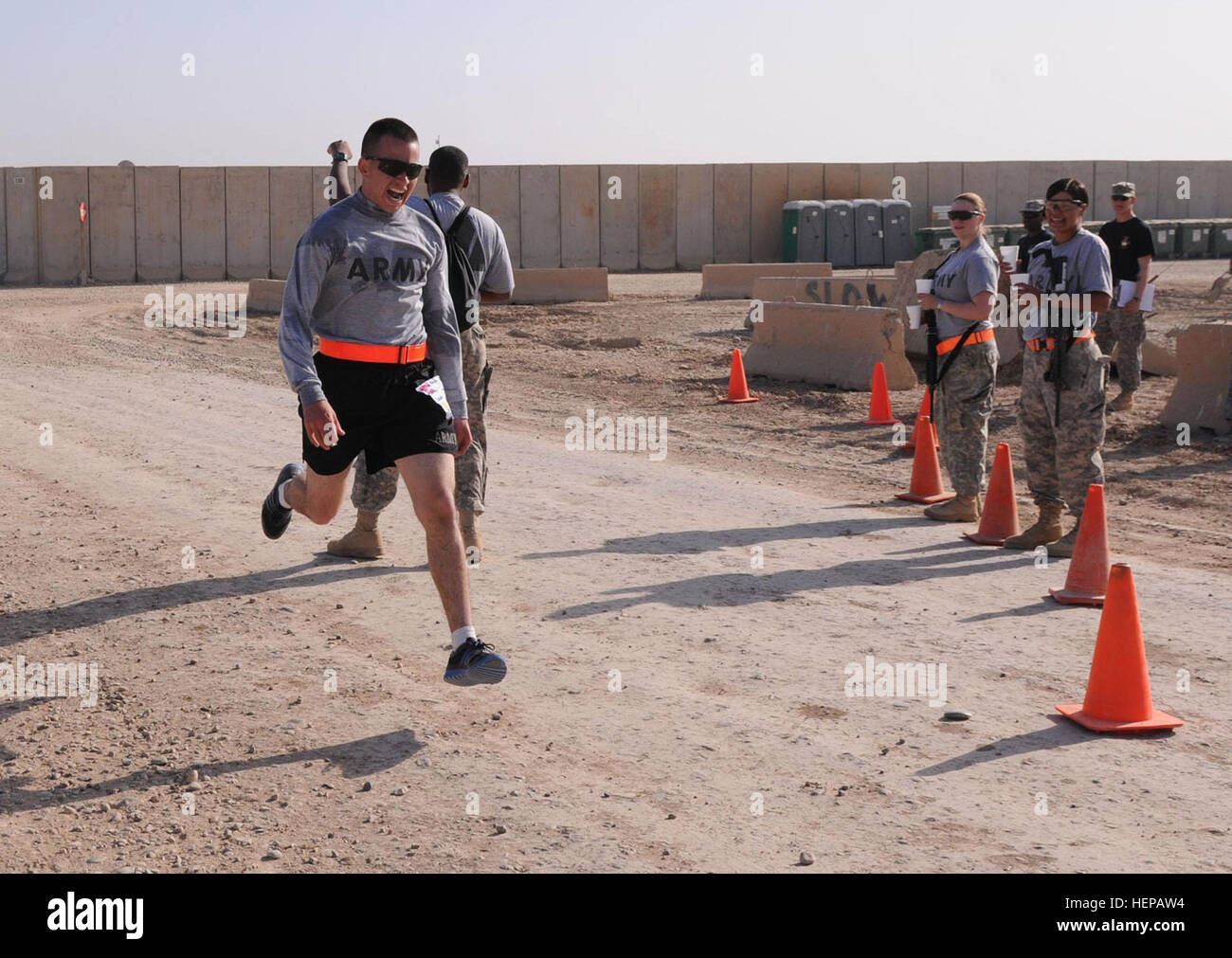 Spc. Joshua Sanchez, a signal support systems specialist from Grand Junction, Colo., 556th Signal Company, 225th Brigade Support Battalion, 2nd Advise and Assist Brigade, 25th Infantry Division, races into the finish line following a six-minute pace to finish first during the Great Aloha Run, March 6, at Contingency Operating Base Warhorse, Iraq. Following the race, awards were presented to the top three finishers in each age group, as well as plaques for Sanchez, who placed first overall for the men's category with a time of 53 minutes, 06 seconds; and 1st Lt. Kryistal Patrick, a something fr Stock Photo