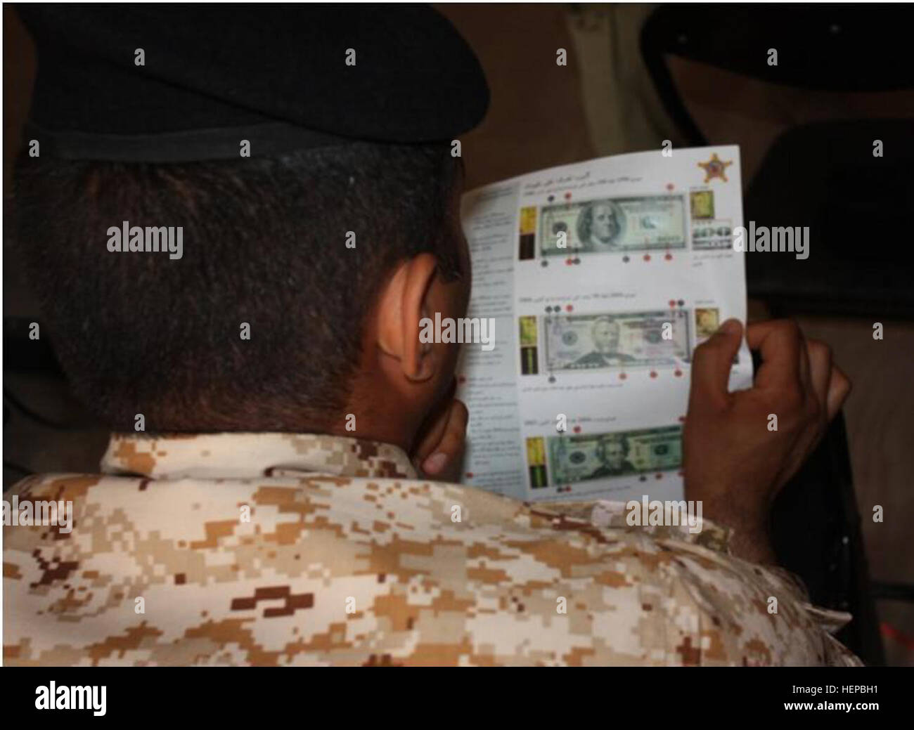 A Maysan province policeman looks at examples of counterfeit currency