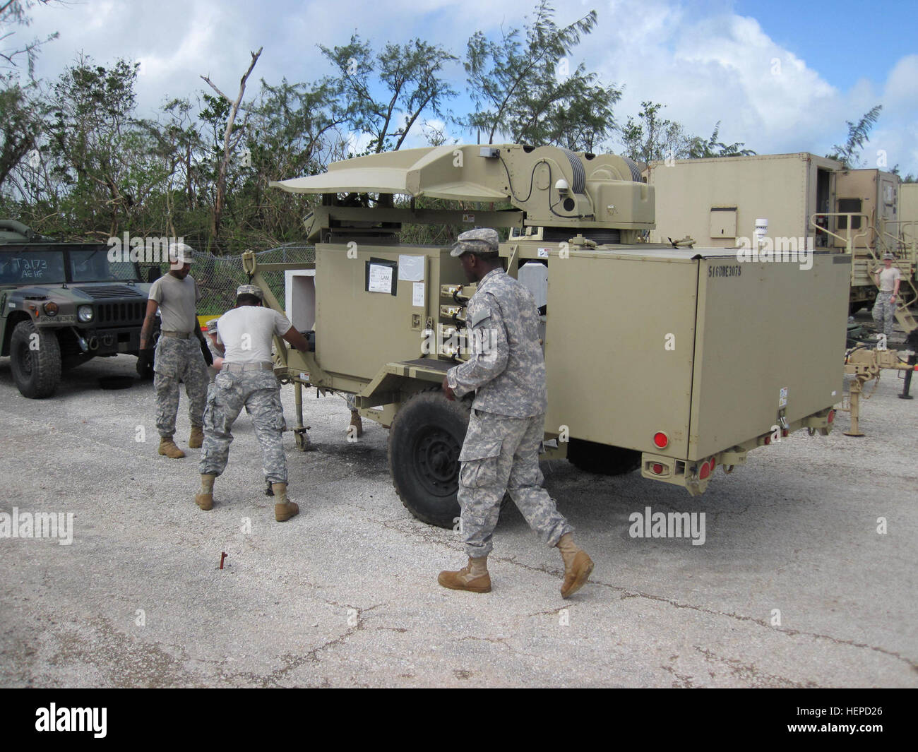 Army Spc. Paul Latimer (left) from Battery D, 2nd Air Defense Artillery Regiment and Sgt. Jarius Bruce (middle) and Spc. Brandon Fuller (right), both from the 307th Signal Battalion emplace communications equipment after the passing of Typhoon Dolphin. The strong storms that strike Guam can be destructive, but it will never break the confidence Task Force Talon Soldiers have in their training and the support from the joint community on Andersen Air Force Base, Guam. (U.S. Army photo by Maj. Jonathan Stafford, executive officer, Task Force Talon, 94th Army Air and Missile Defense Command) Power Stock Photo
