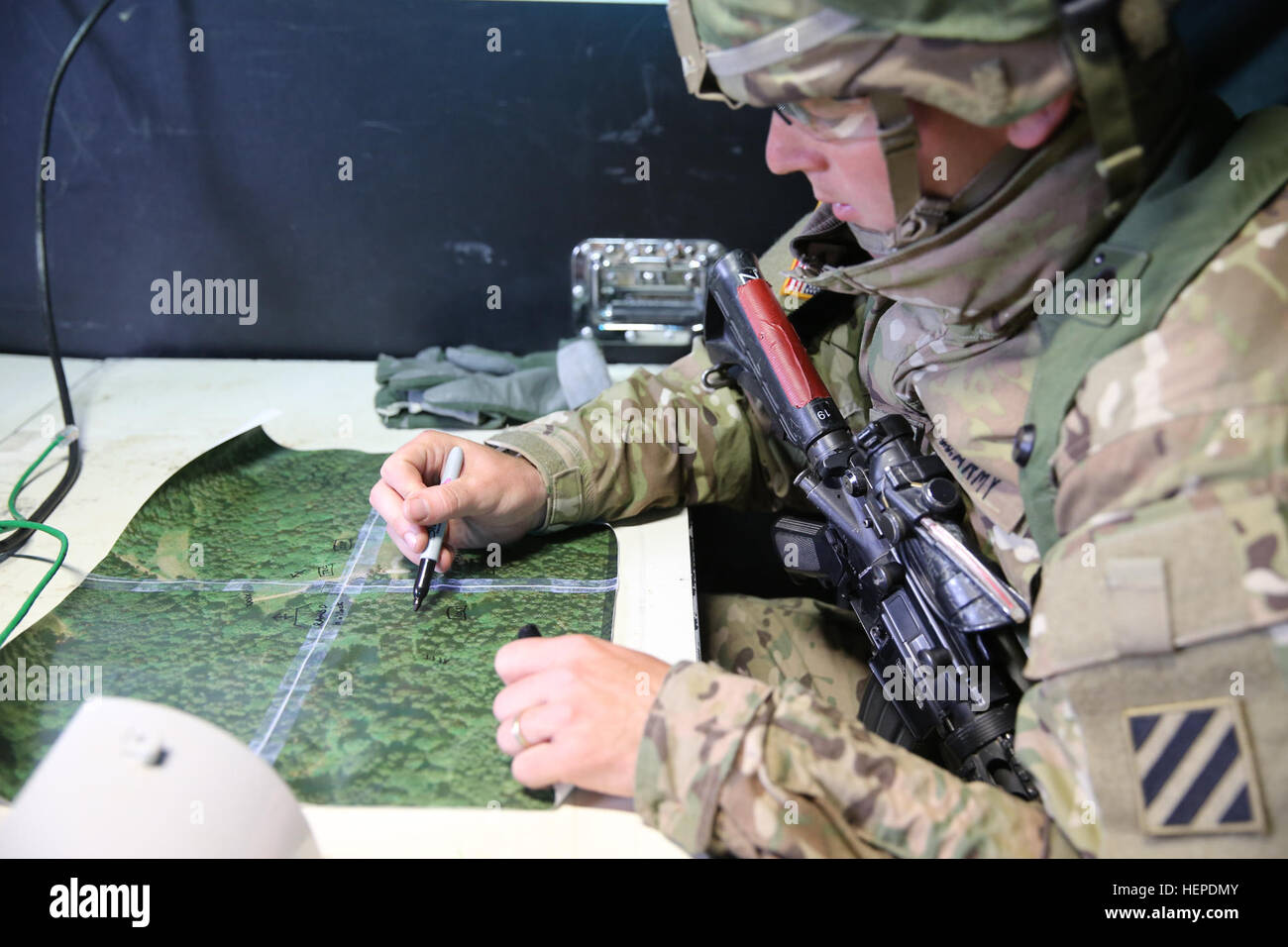 A U.S. Soldier assigned to the 1st Battalion, 41st Field Artillery Regiment, 1st Armored Brigade Combat Team 3rd Infantry Division plots points on a map in a tactical operations center during exercise Combined Resolve IV at the U.S. Army’s Joint Multinational Readiness Center in Hohenfels, Germany, May 27, 2015. Combined Resolve IV is an Army Europe directed exercise training a multinational brigade and enhancing interoperability with allies and partner nations. Combined Resolve trains on unified land operations against a complex threat while improving the combat readiness of all participants. Stock Photo