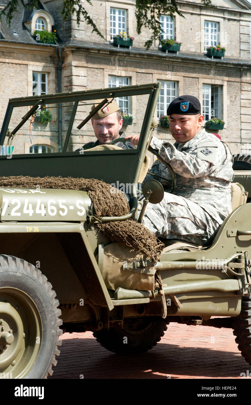 Staff Sgt. Jose Policarpo, with the 4th Infantry Division drives a World War II era jeep of Vince Trotoux, a re-enactor. 'I don't want those who died to be forgotten. Those who enjoy liberties have to be reminded that someone died for them. When a veteran thanks you for keeping the memories alive, it's like those men will live forever. It's important. The goal of human people is to leave a part of your history, and this is why do it,' Troutox said when asked why he does the re-enactments. On June 3, 2015, the town of Carentan, France, hosted service members of the Joint Task Force D-Day 71. Th Stock Photo